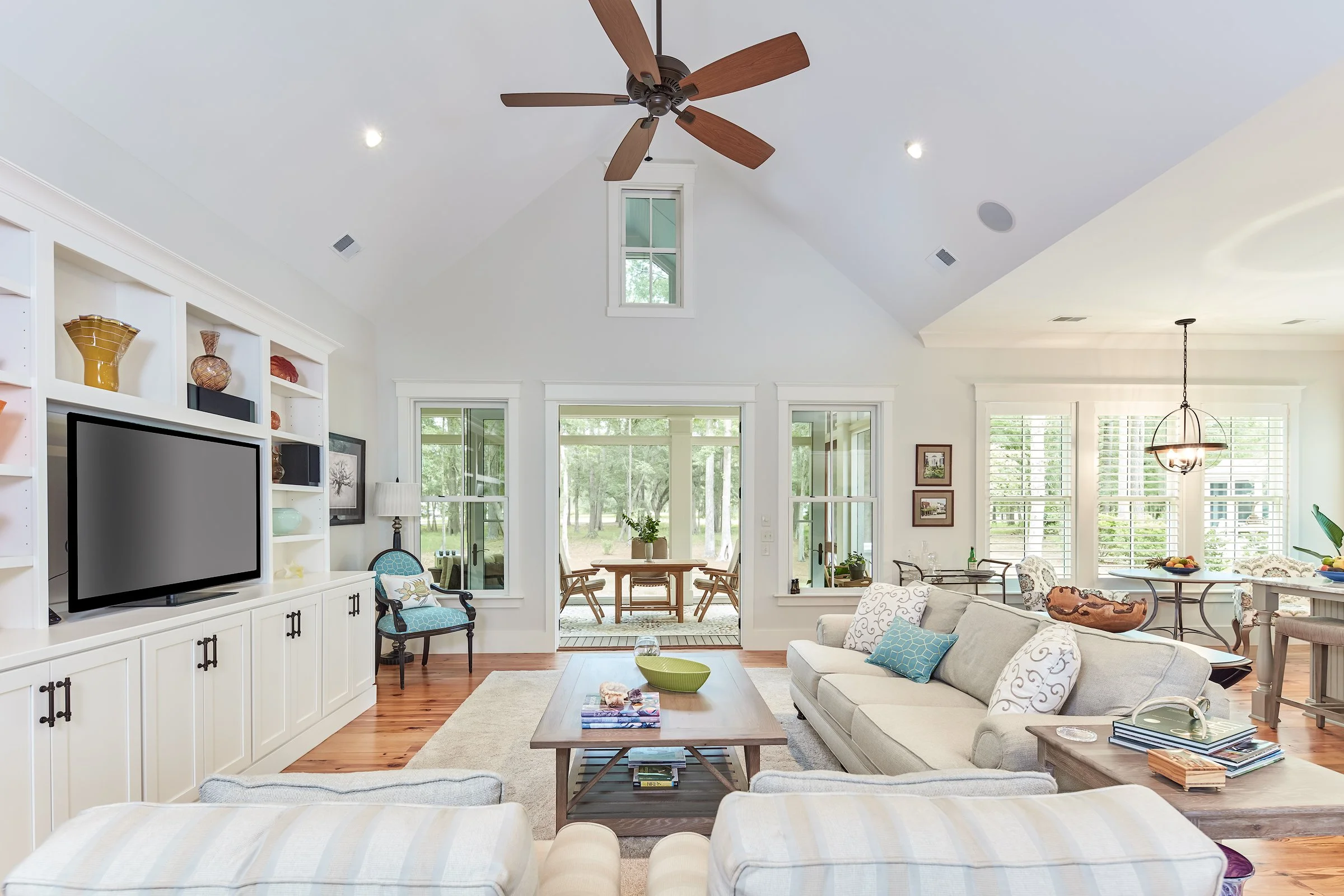 a luxurious open floorplan living room with vaulted ceilings. Doors open onto a screened in back porch.