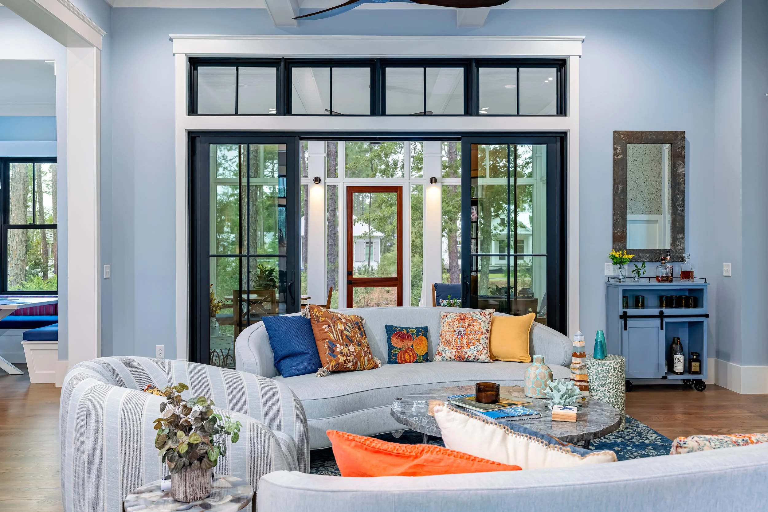 A beautiful blue lining room with high ceilings thick molding and French door opening onto a screened in patio.