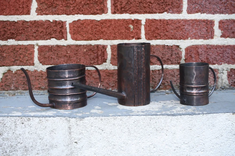 The suite of three (3) copper, fold formed watering cans.