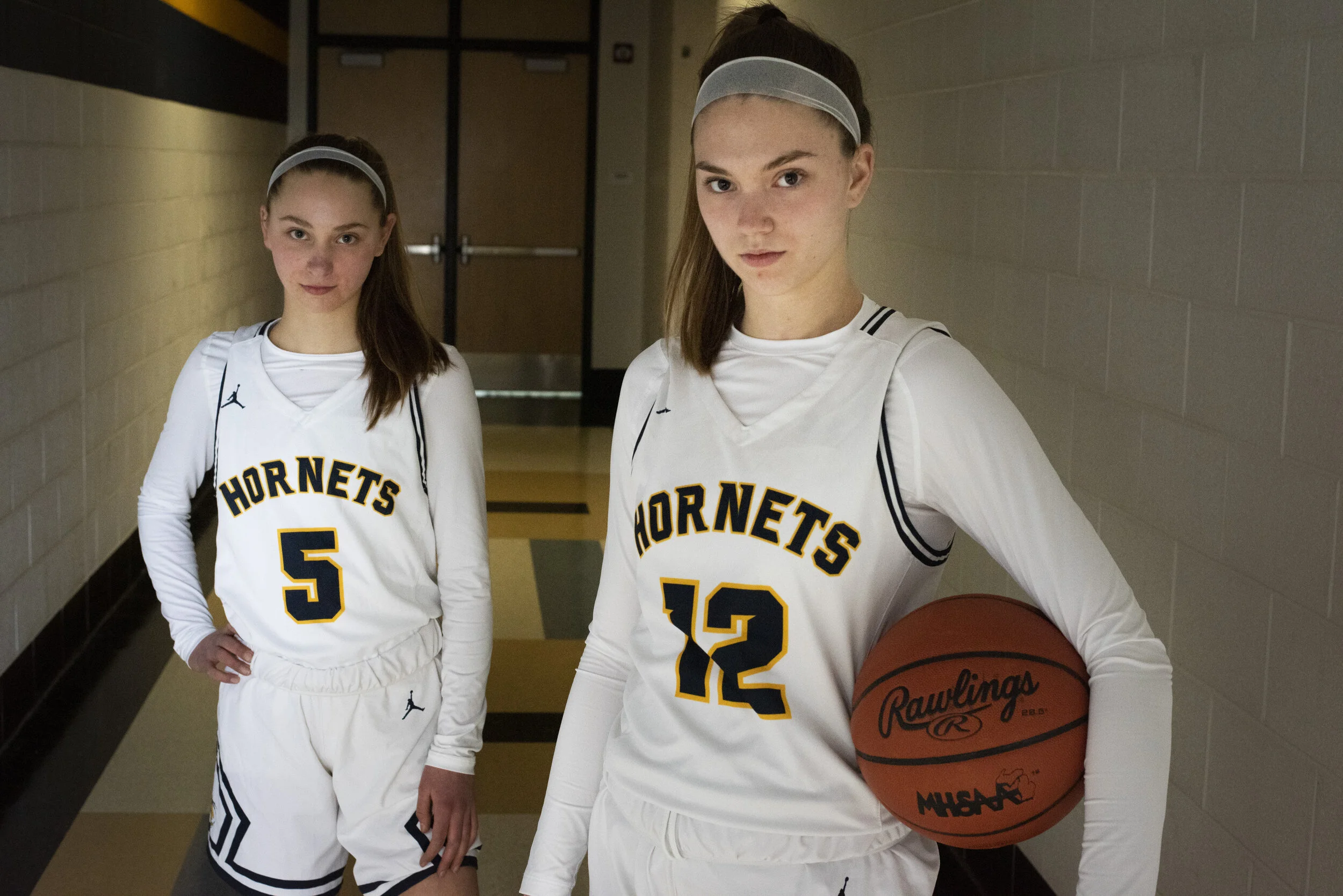  Ella Stemmer, senior, right, and her younger sister Kate, freshman, in the halls of Saline High School before a game on Monday, March 8, 2021. Ella and Kate have been training with their father since they were young, and the 2020-2021 season was the