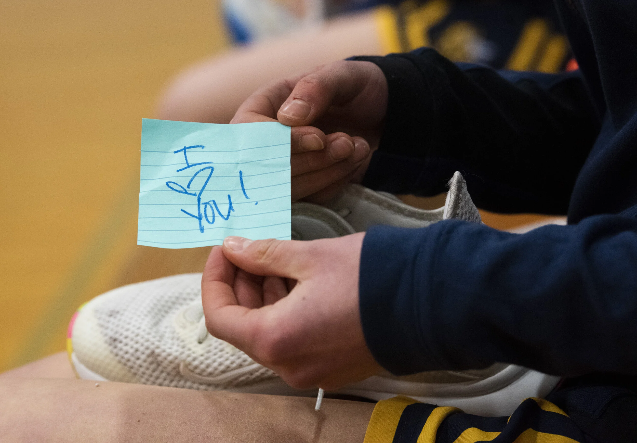  Kate Stemmer pulls a note from her mother out of her shoe while she’s putting her shoes on at Monroe on Friday, March 5, 2021. Their mother put notes and a toy in the girls shoes as a surprise before they headed out onto the court. 