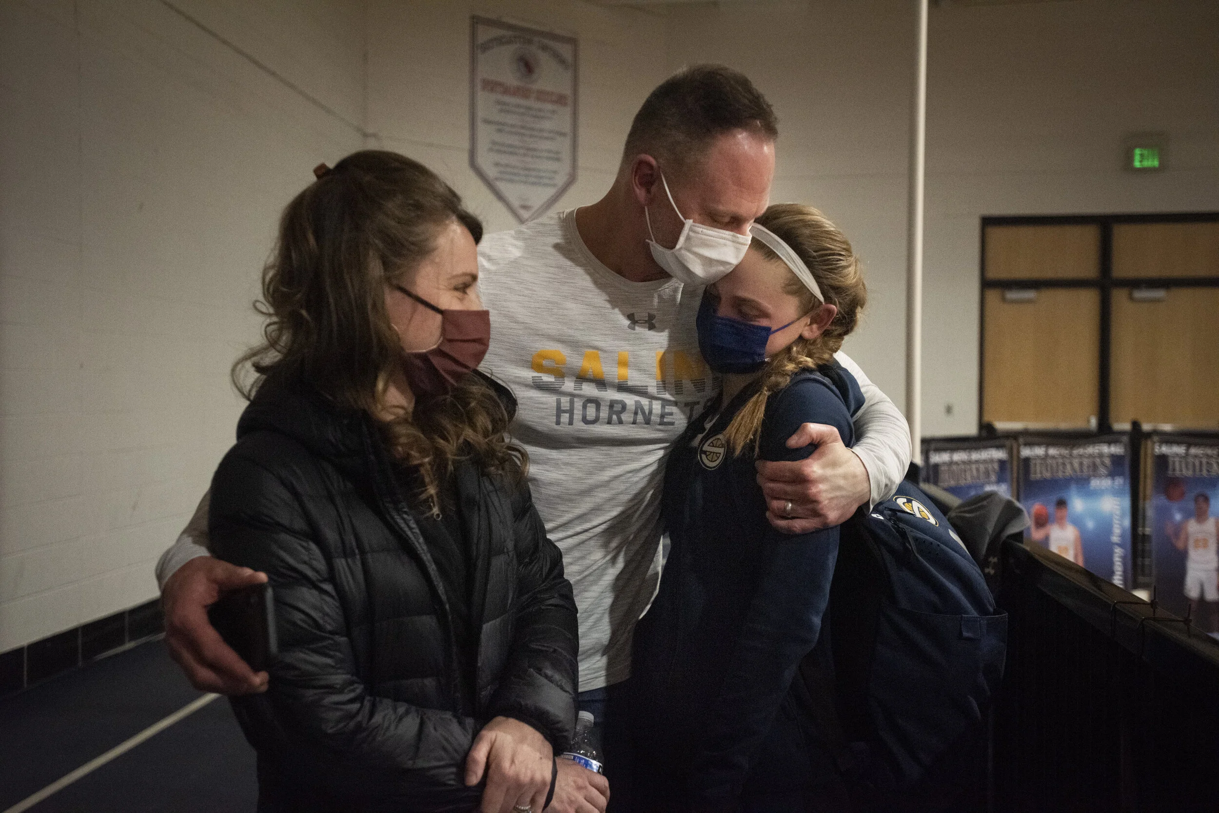  Eric Stemmer, center, embraces Kate after a game along with her mother, Kara, on Thursday, March 11, 2021. Eric and Kara attend every game the girls play. Growing up, Eric coached the girls travel basketball teams. This year, since the girls were fi