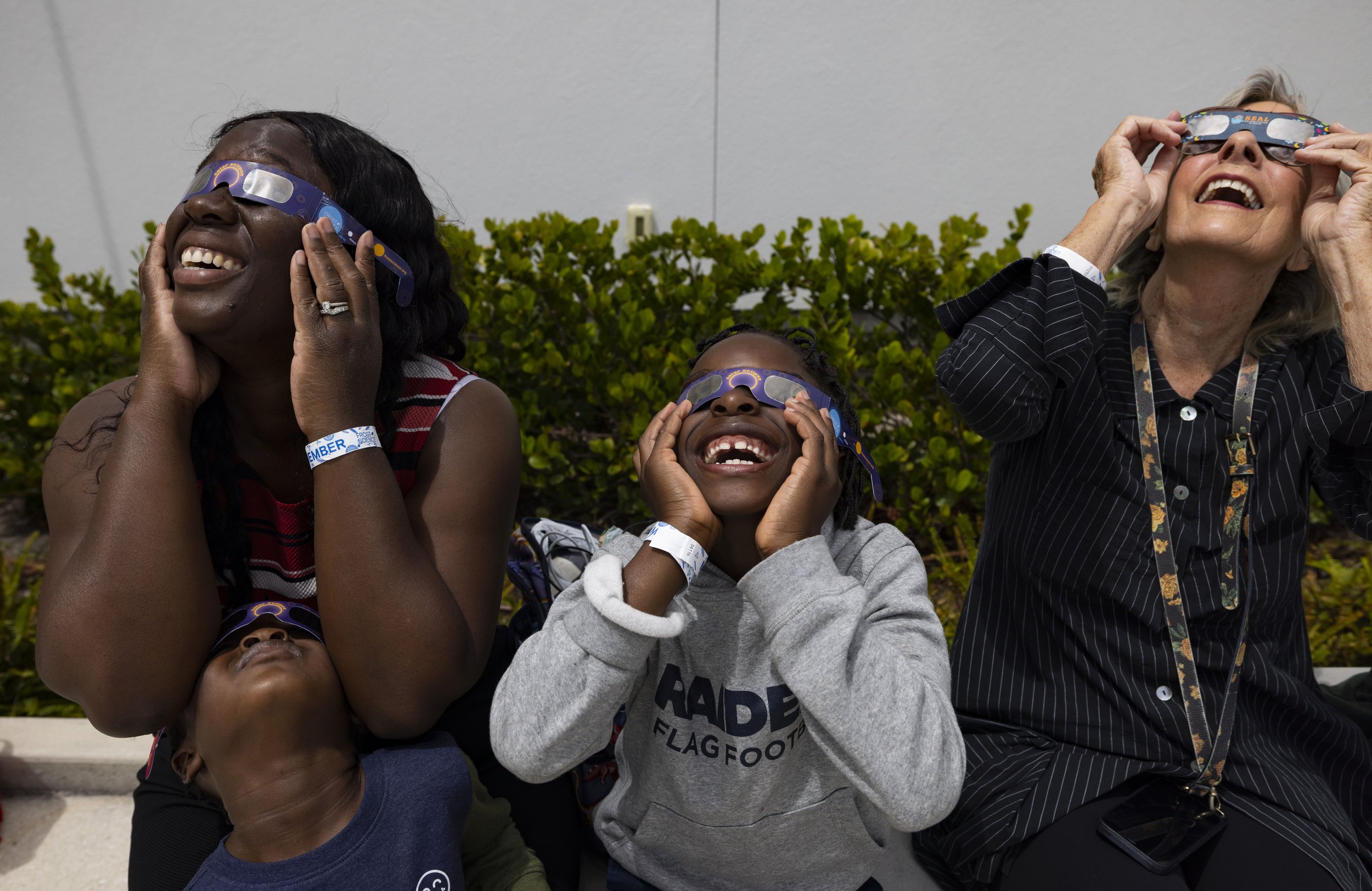Nathalie Blanfort, left, and her sons, Noah, 4, and Bryson, 6, watch the solar eclipse with Doris Ugarriza, right, on the roof of the museum on Monday, April 8, 2024, at The Phillip and Patricia Frost Museum of Science in downtown Miami. “Oh my gosh