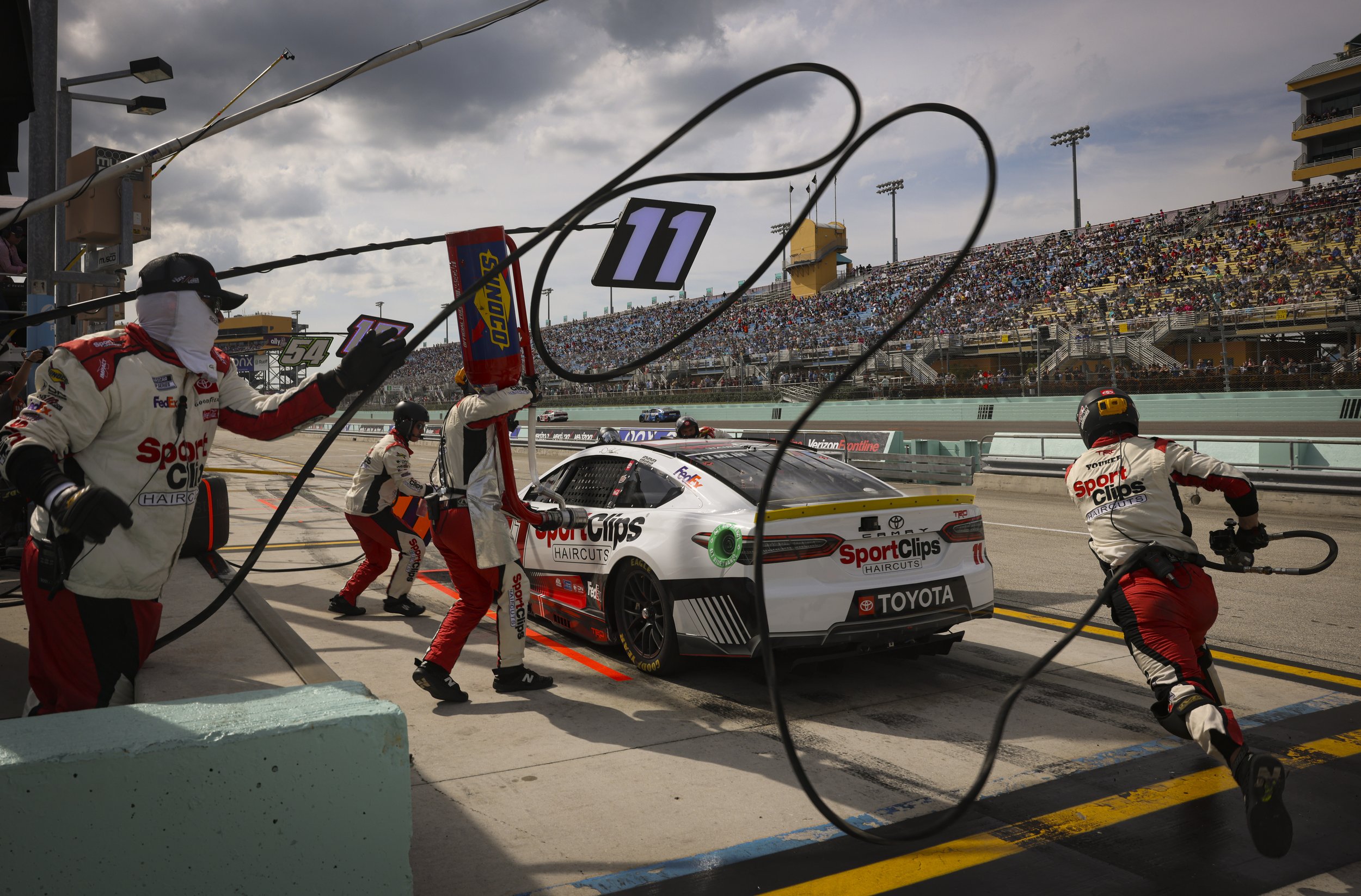 Denny Hamlin (11) comes in for a pit stop and his crew rushes to tend to the car during the NASCAR 4EVER 400 Cup Series on Sunday, Oct. 22, 2023, at Homestead-Miami Speedway in Homestead, Fla.