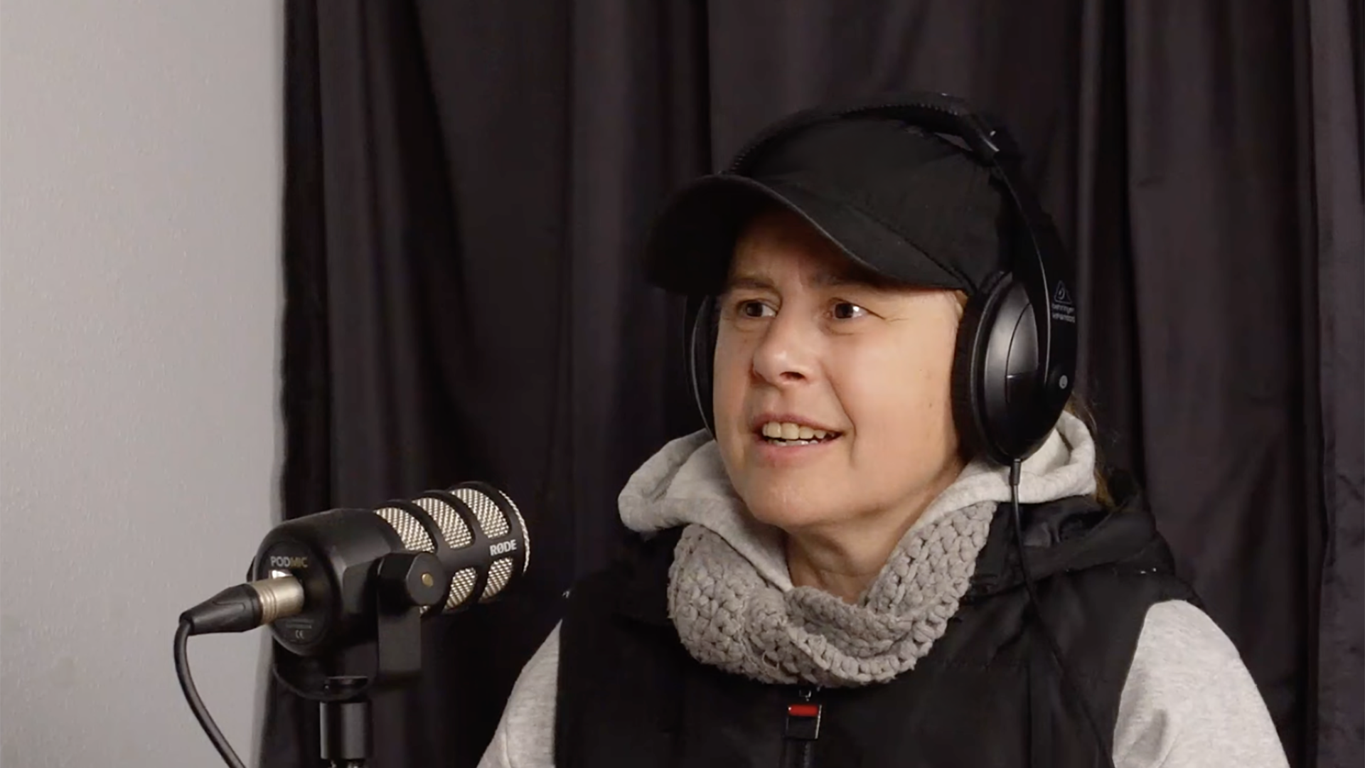 Vickie Simos speaking into a microphone in a recording studio.