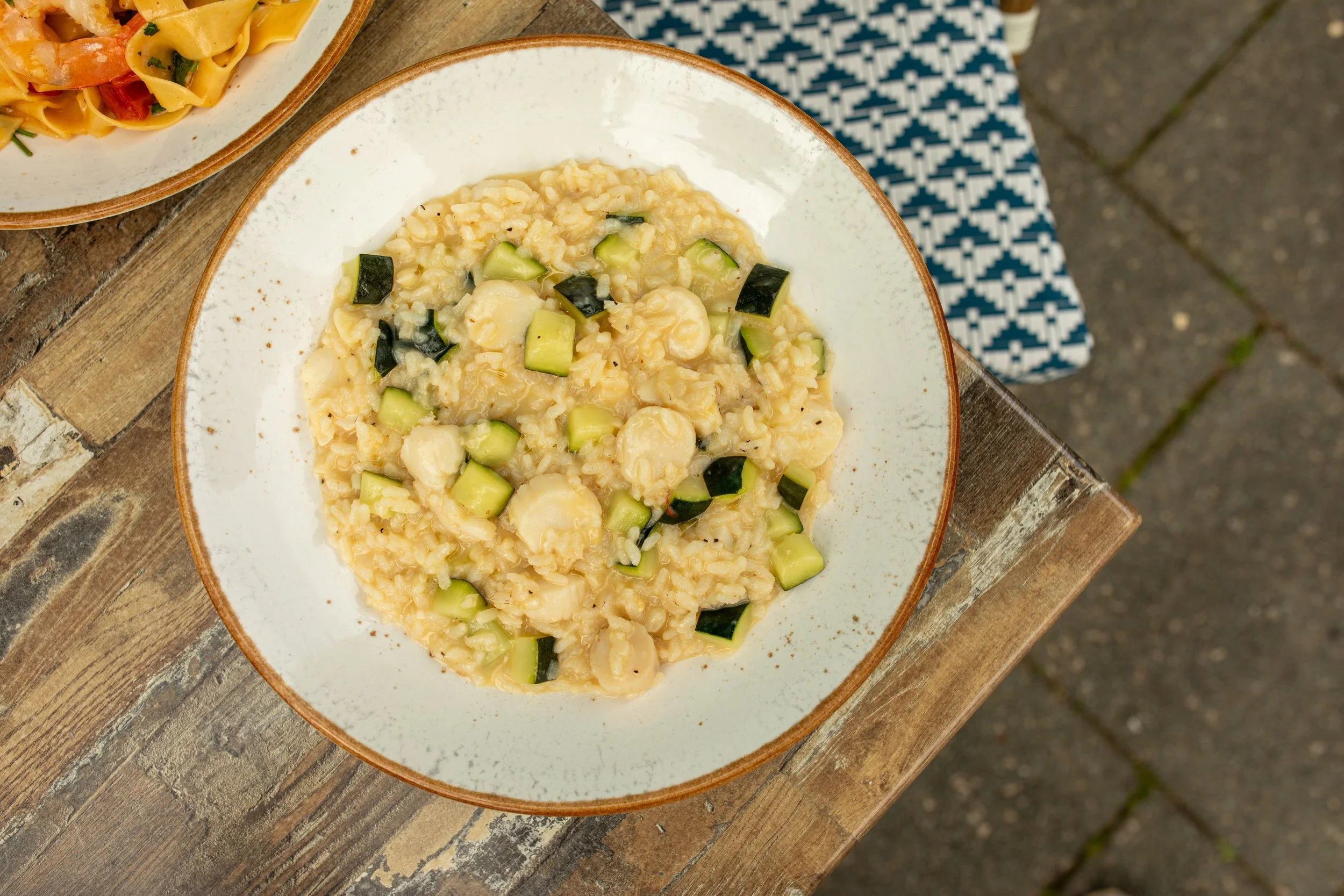 A bowl of risotto with zucchini, served on a wooden table