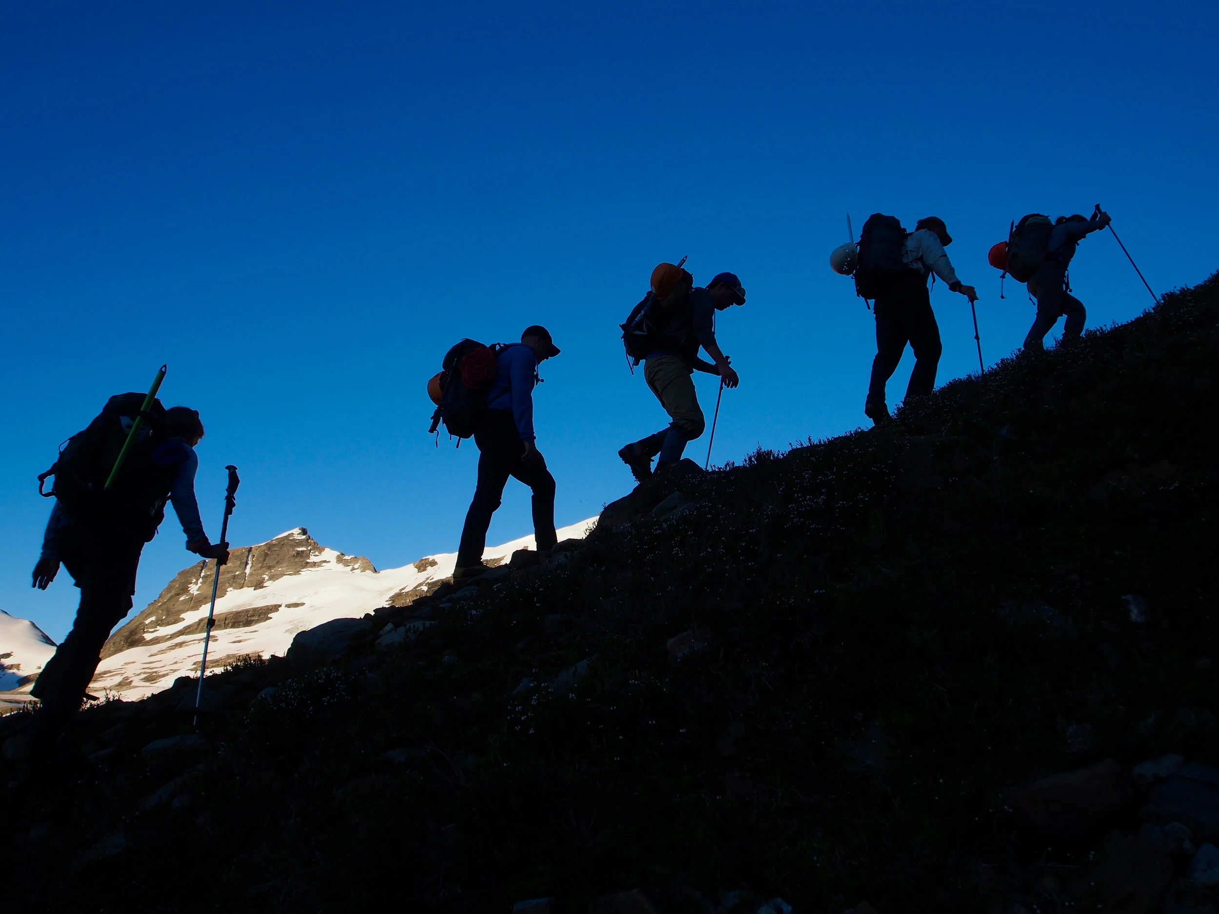 A group of climbers make their way over the moraines leading to the “Riddle “ glacier during week 2 at the 2018 GMC. Climbs on this side the valley called for 4am wake-ups and boots on the trail by 5am. Photo: Jeff Stokoe.