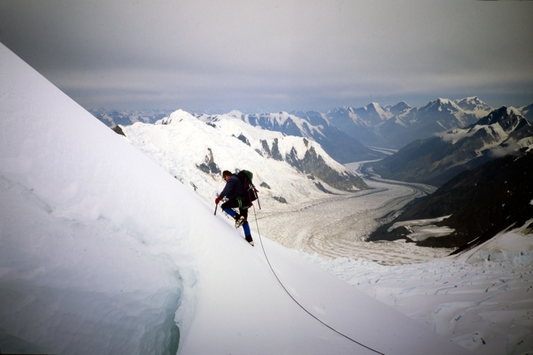  Paul climbing the final pitch to the summit of West Slaggard I. The Anderson Glacier winding its way towards Alaska in the distance. Photo by Bill McKenzie. 