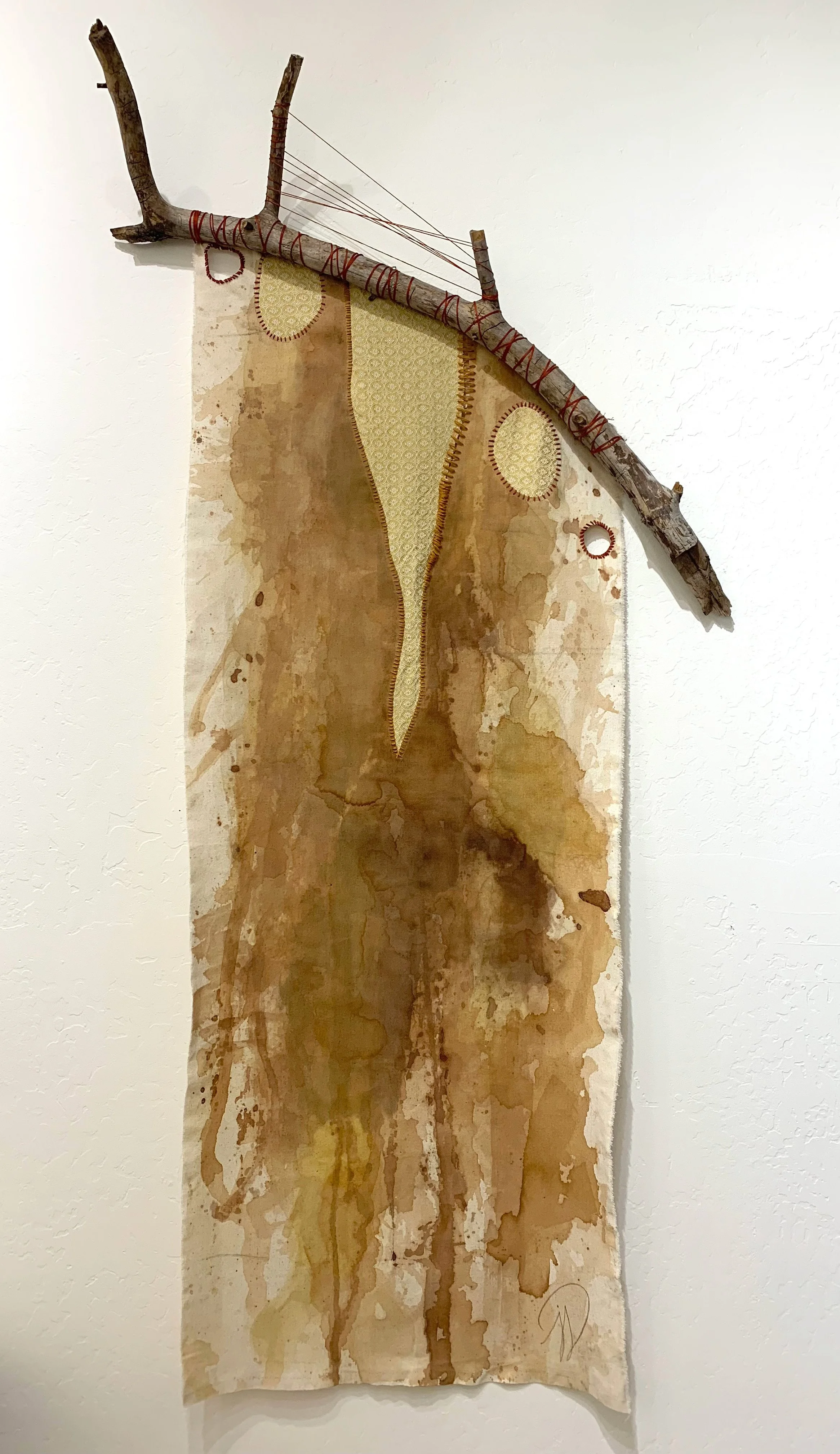Raw canvas painted with ponderosa pine ink and turmeric ink suspended from a branch
