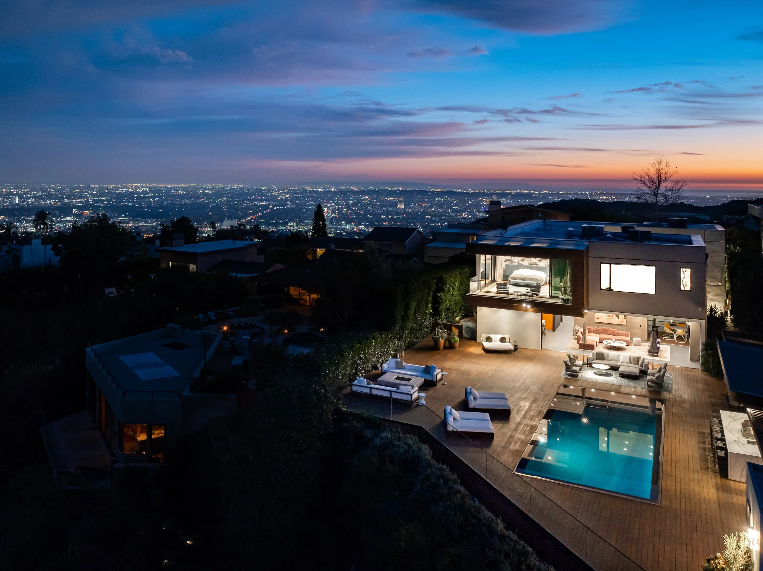 A night aerial view of a luxury home in the hollywood hills and the city lights.