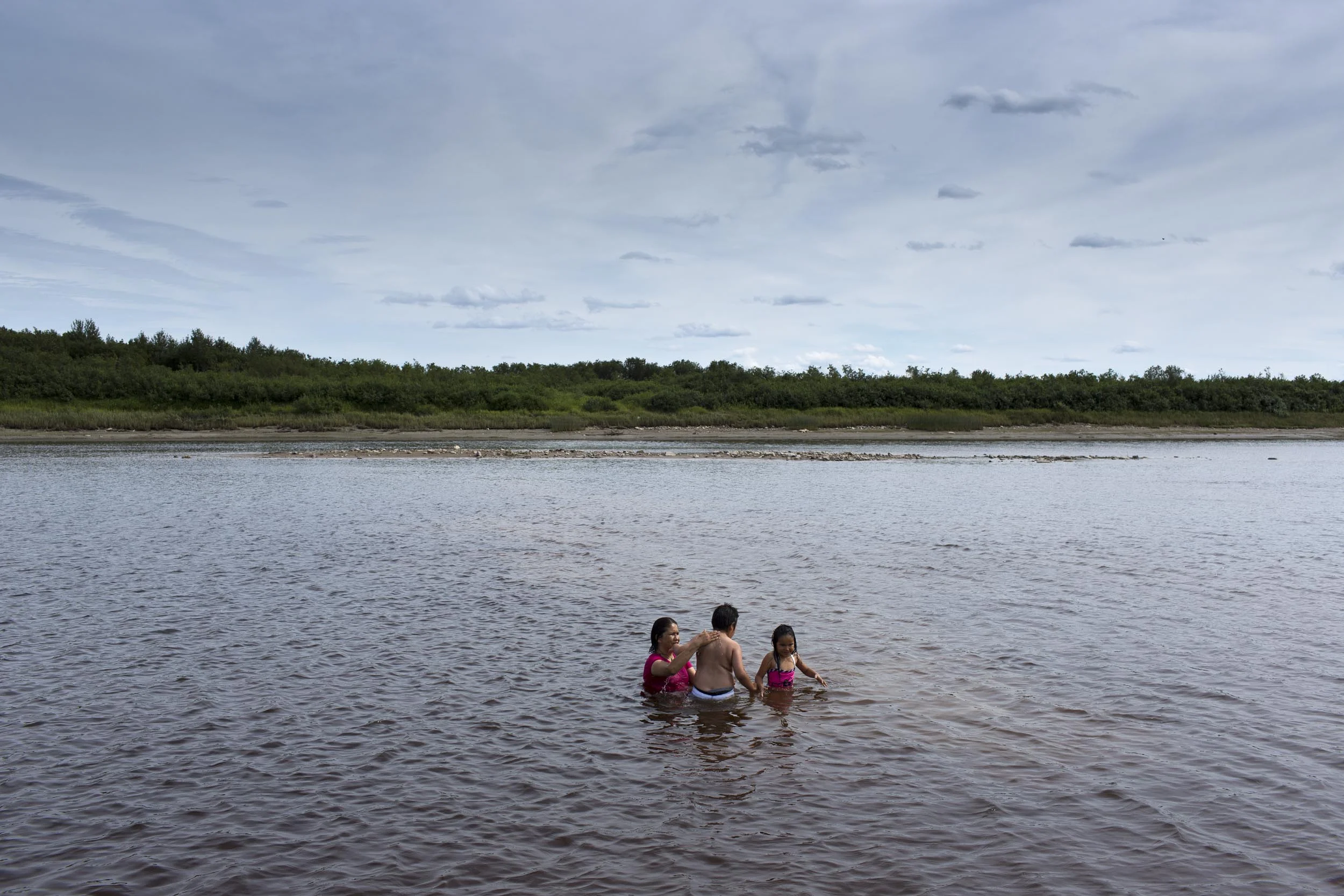 'People of the Parting Rocks' for The Pulitzer Centre on Crisis Reporting . An Auntie swims with her niece and nephew in the Attawapiskat river in Attawapiskat, Ontario.