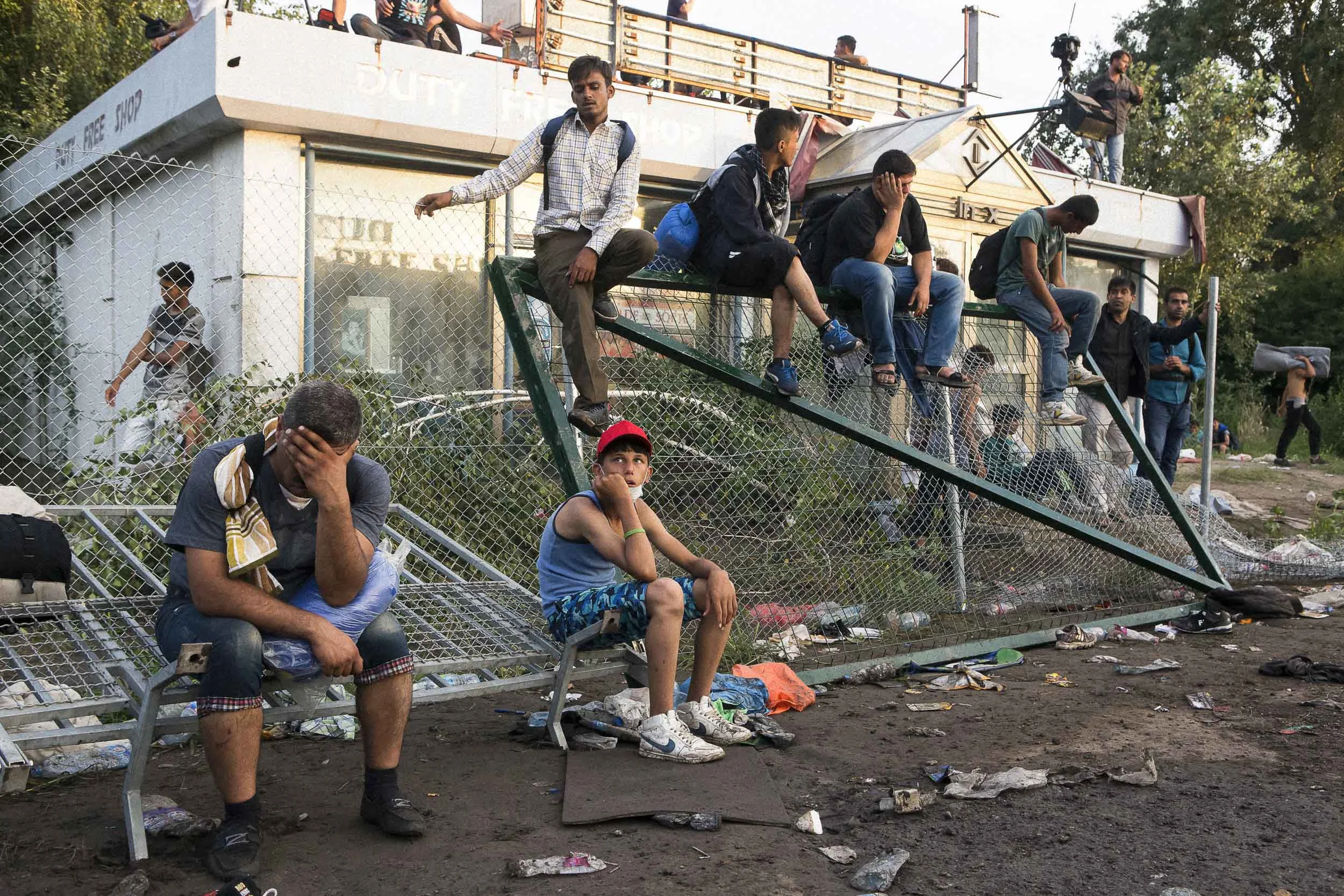 Horgoš, Serbia. Refugees rest on a damaged border fence after a violent clash with Hungarian police guarding the Serbian/Hungarian border.