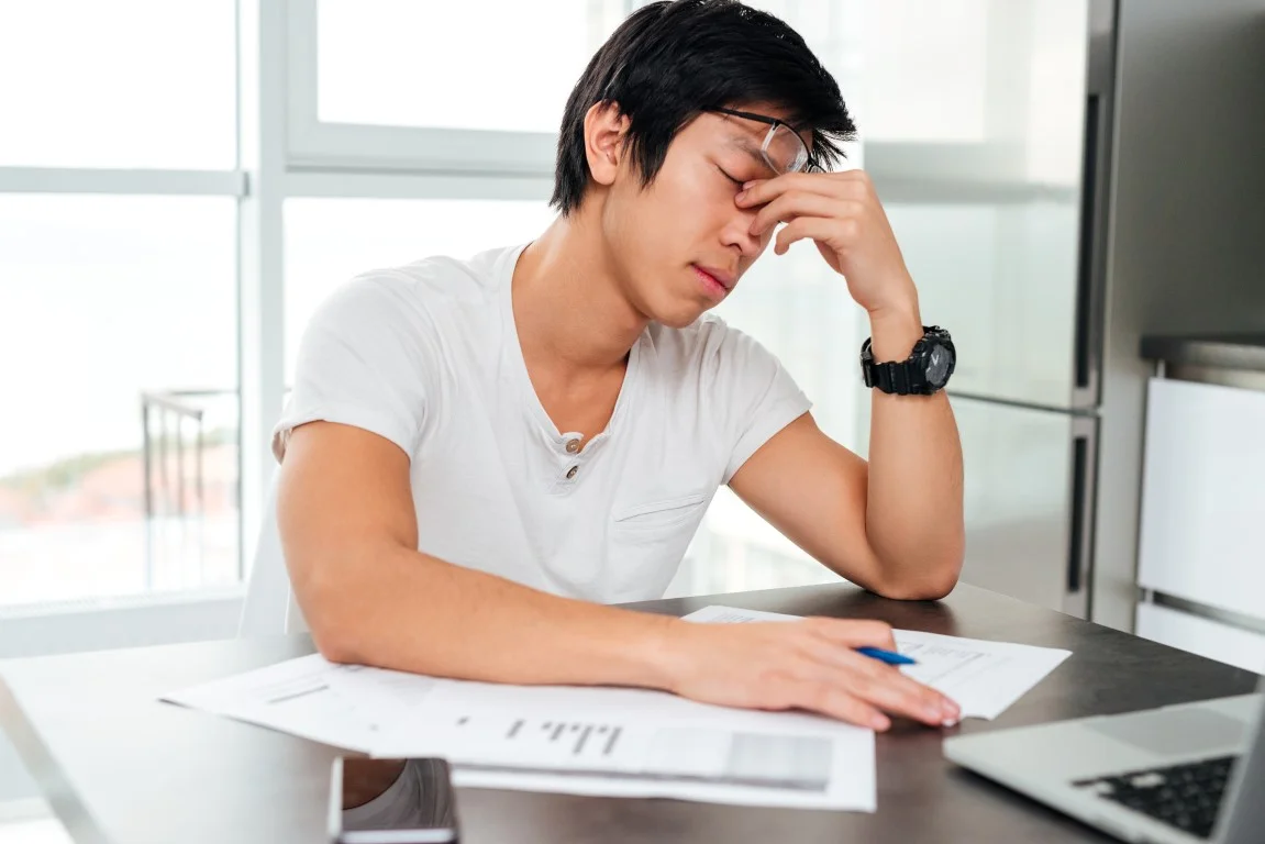 graphicstock-tired-asian-man-by-the-table-with-docements-and-laptop_HO1Jufwhe.jpg