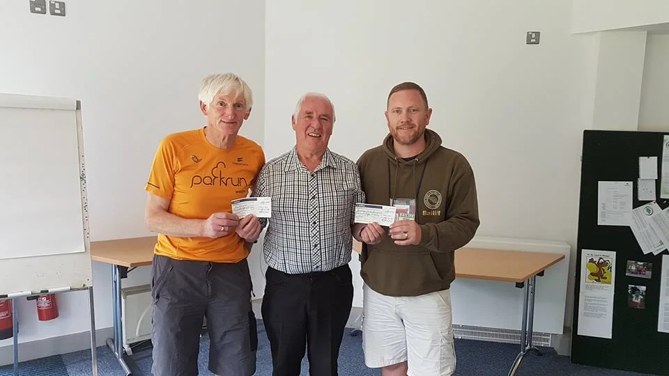 CLUB TREASURER JAMES ACCEPTING A DONATION FROM CLLR IAN DUNBAR.