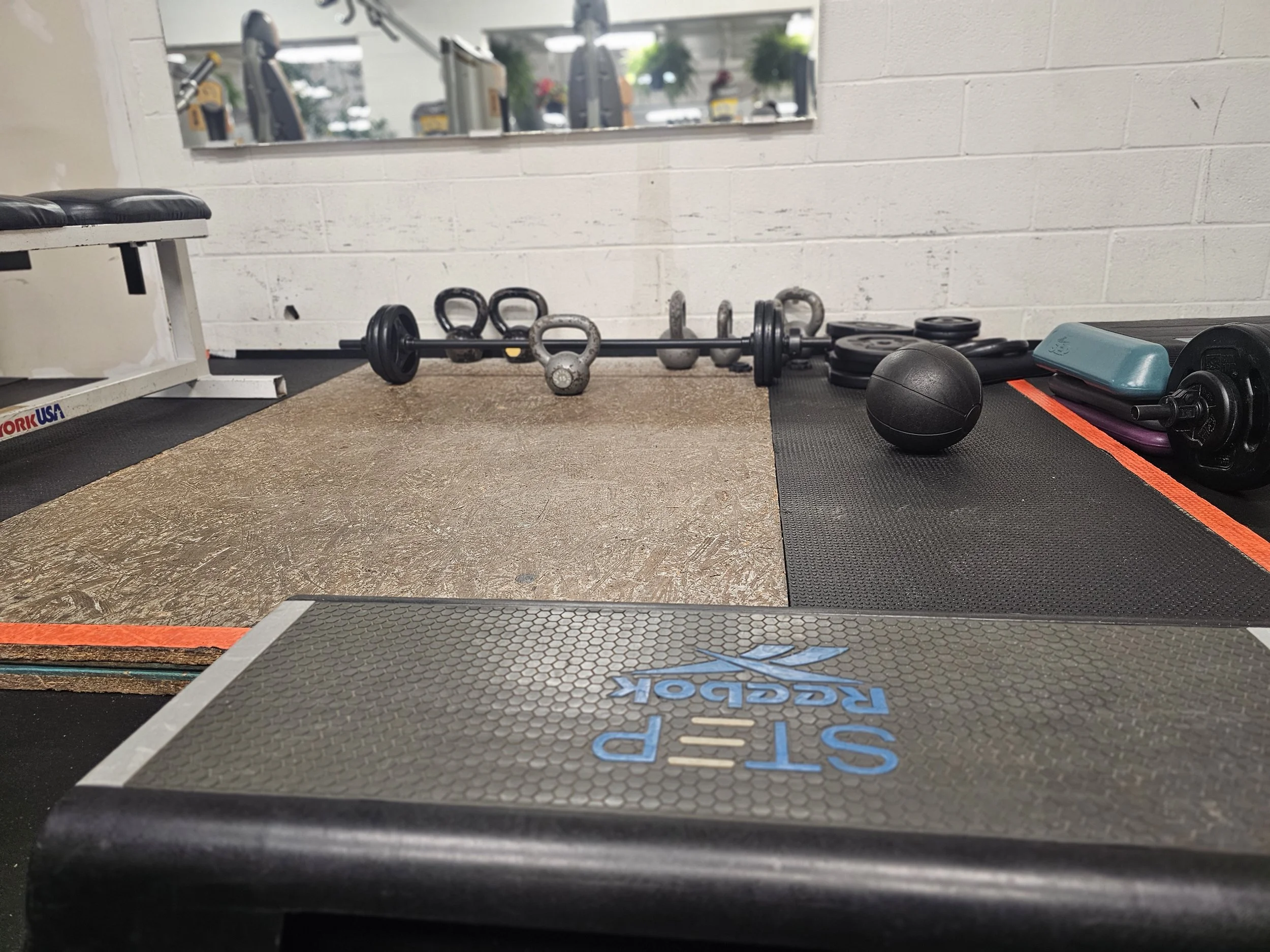 Kettle bells, barbells, and dumb bells available to use at the bench in the women's weight lifting area in State College, PA