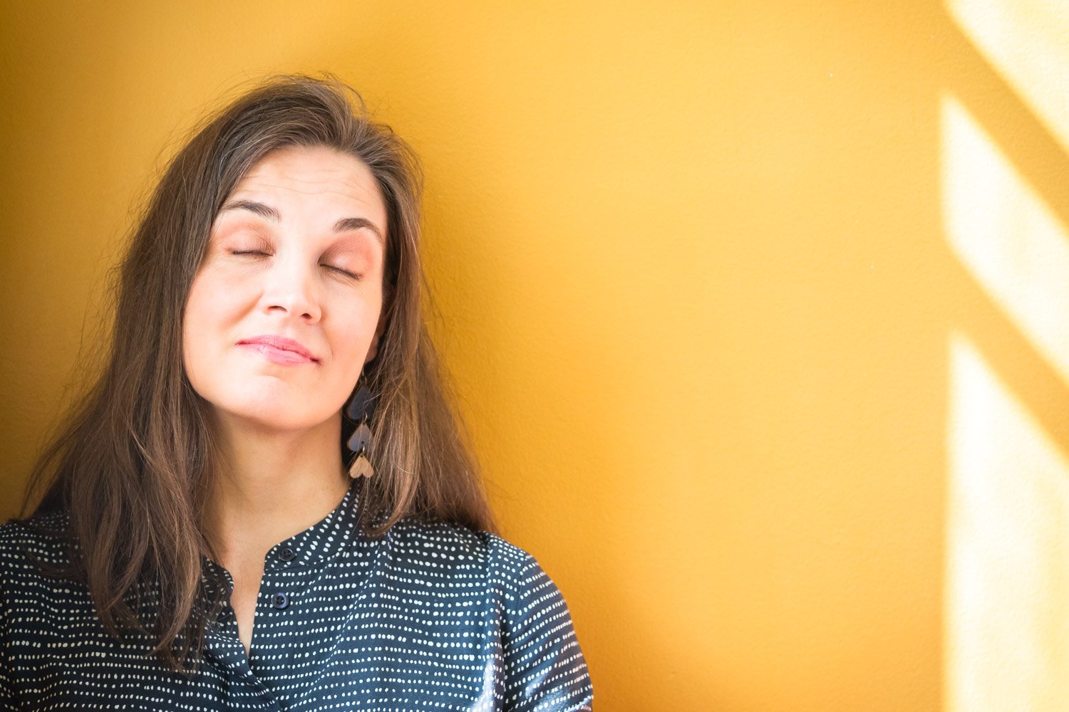 Valokuvassa kirjailija Tuutikki Tolonen, keltainen tausta ja luonnonvalo ikkunasta