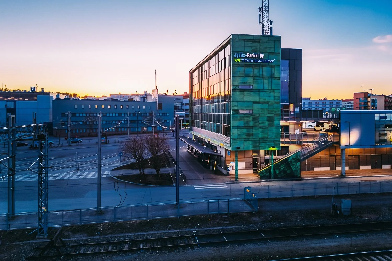 Dronekuva iltaöisestä Jyväskylästä, auringonlasku heijastuu Jyväs-Parkki Oy:n rakennuksen ikkunoista
