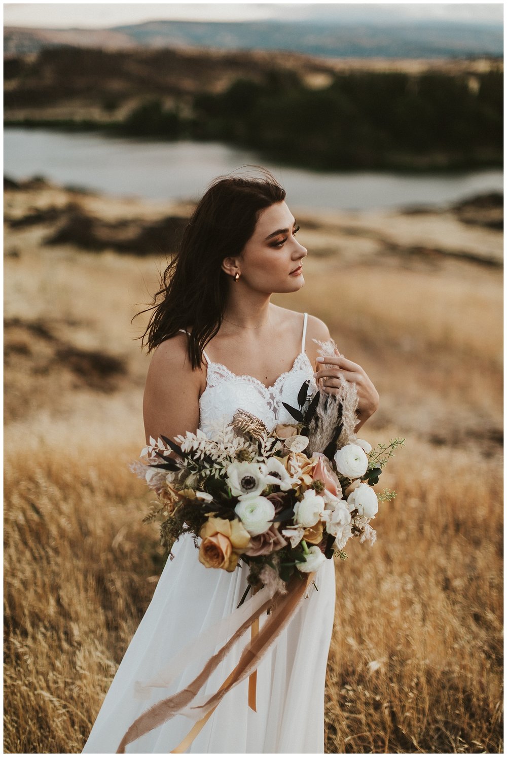 a bride in a flowing white gown holds a large bouquet and looks off into the distance