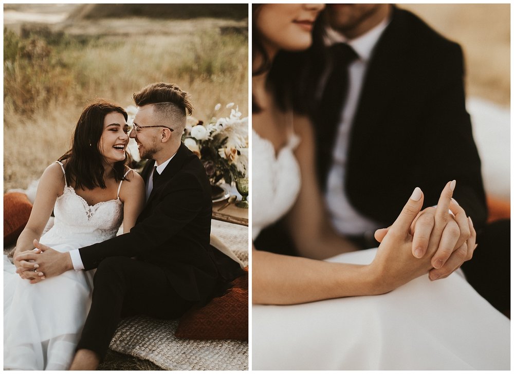 a bride and groom sit together and laugh and hold hands