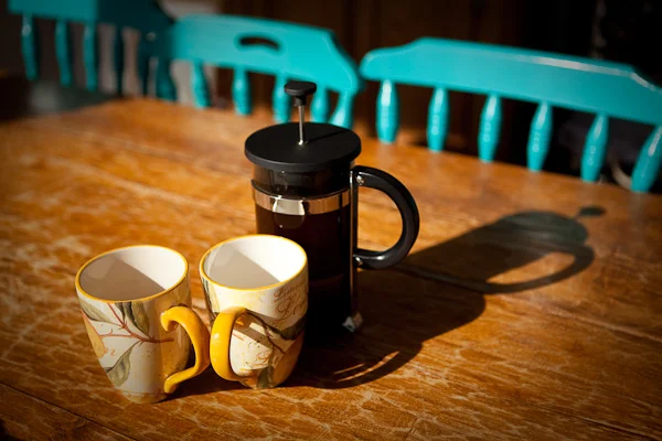Coffee plunger and mugs on a wooden table