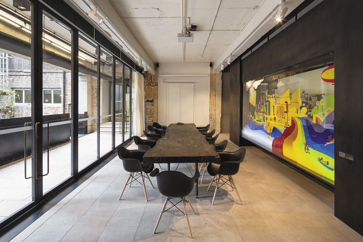 A concrete boardroom with a wooden table matched with a mural with vibrant colors