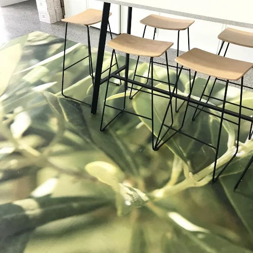 A natural plant designed rug against a monochrome table and wooden chairs