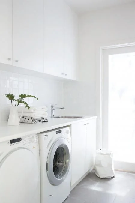I adore this all white laundry. Clean and bright, even though it is a very small space it doesn't feel cramped. The white tile splash back gives some light reflection which is an added bonus in small spaces. Going for a light floor tile is ideal in this situation as it doesn't draw attention to how small the floor space actually is.