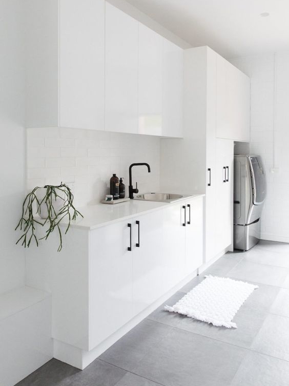 This slick white laundry looks beautiful. Something like this could easily be achieved for people on a tighter budget with pre-made white cabinetry. Black handles and taps are easily assessable and affordable from home project stores. I love that they have included a full height cupboard, perfect for brooms, ladders and ironing boards.