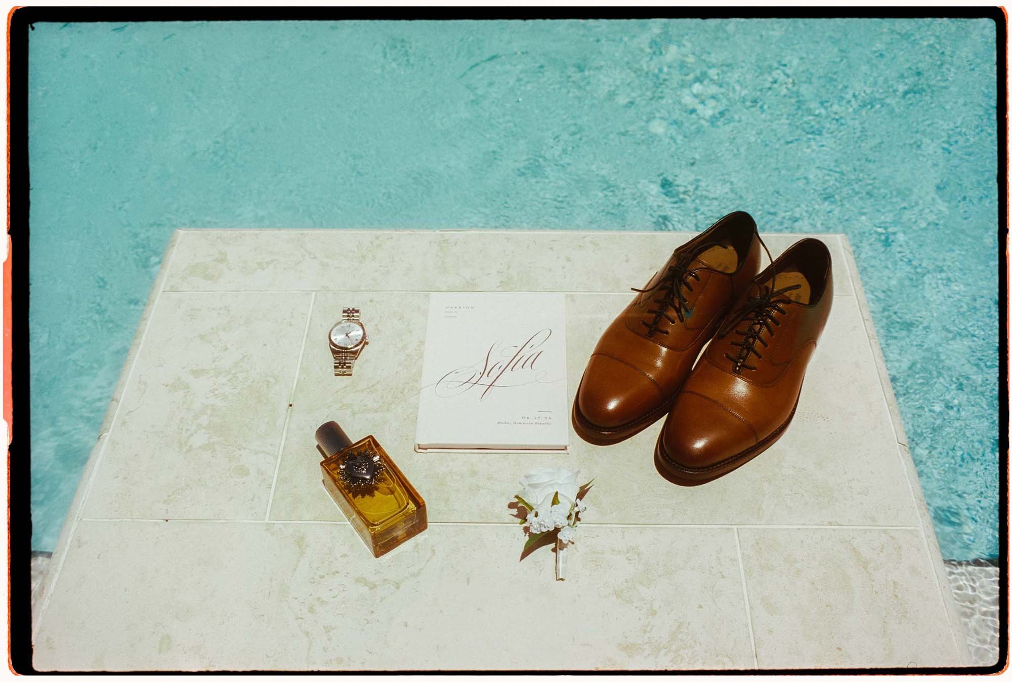 35mm film photo of the details of the groom close to a pool