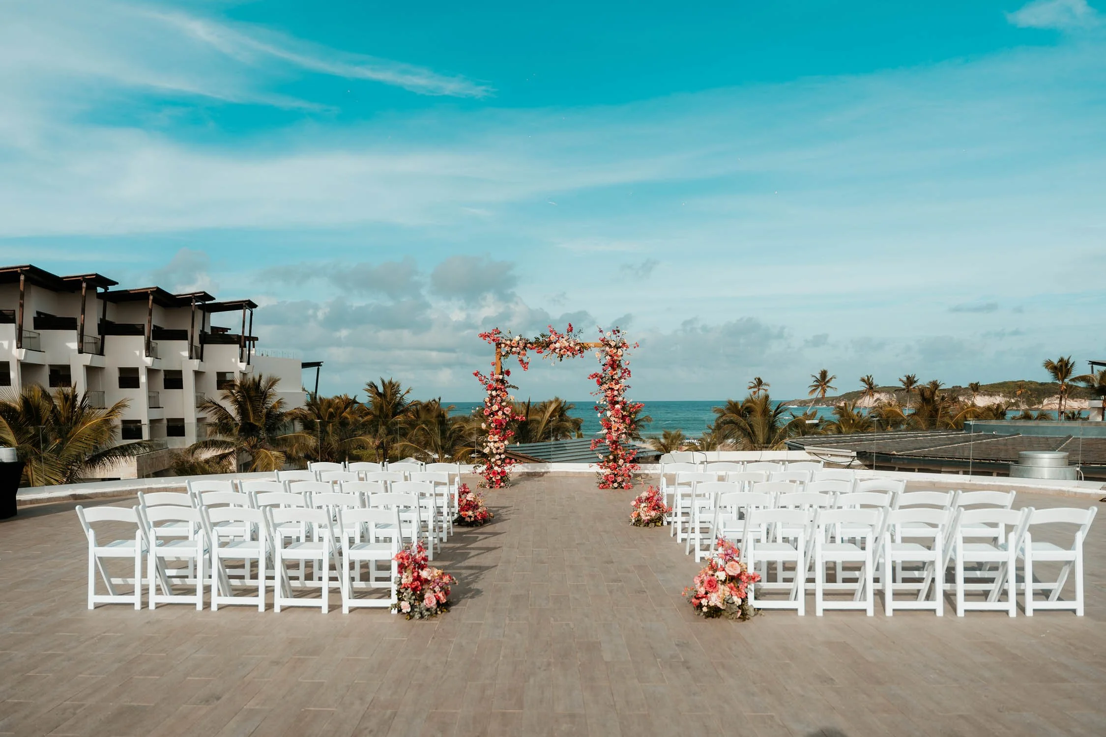 Open and wide ceremony setting with clear blue sky and lots of colorfull flowers arragements