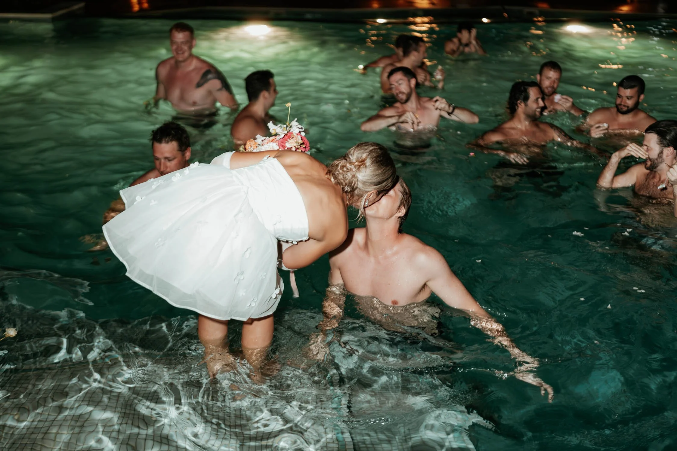 bride and groom kiss at the pool
