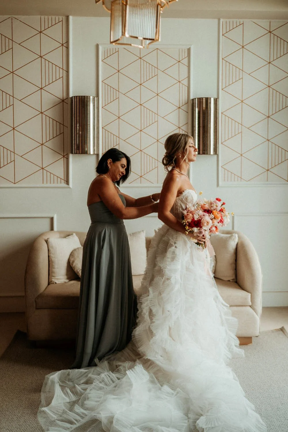 Mother of the bride helping her getting dress with the wedding dress