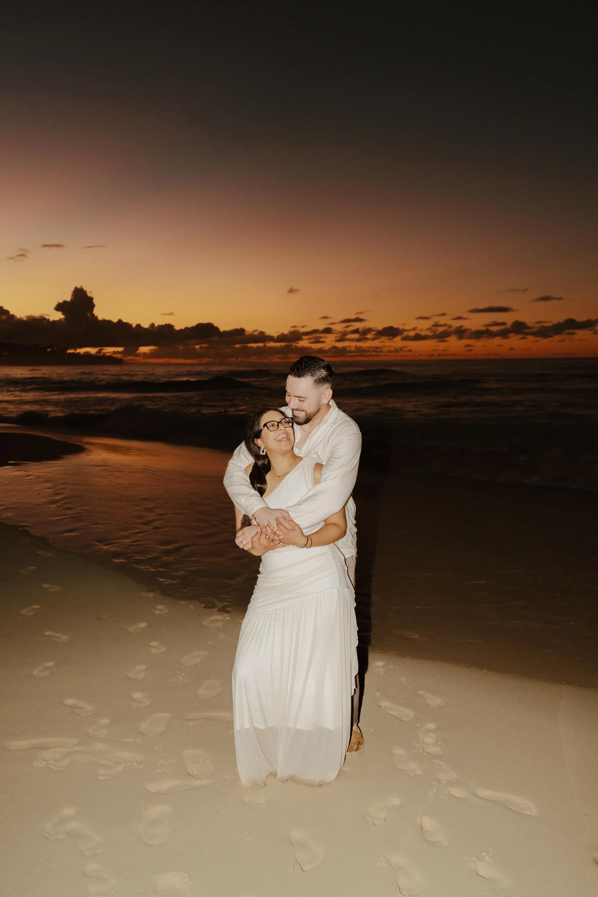 Kamil and Harrison embracing at sunset in Playa Grande, Cabrera, during their luxury destination wedding session