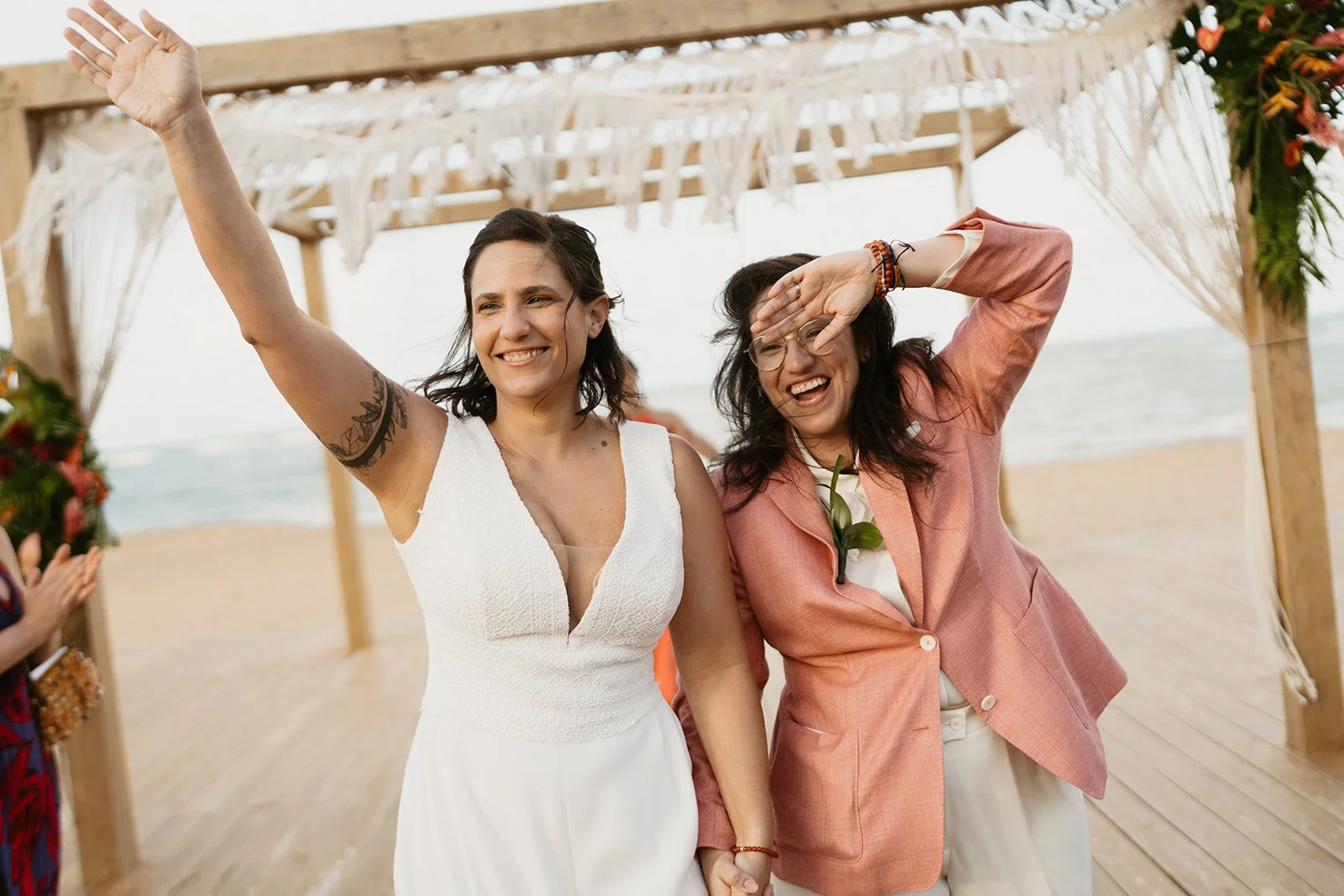 A same sex couple after the first walking down the aisle and waving their hands to the guests
