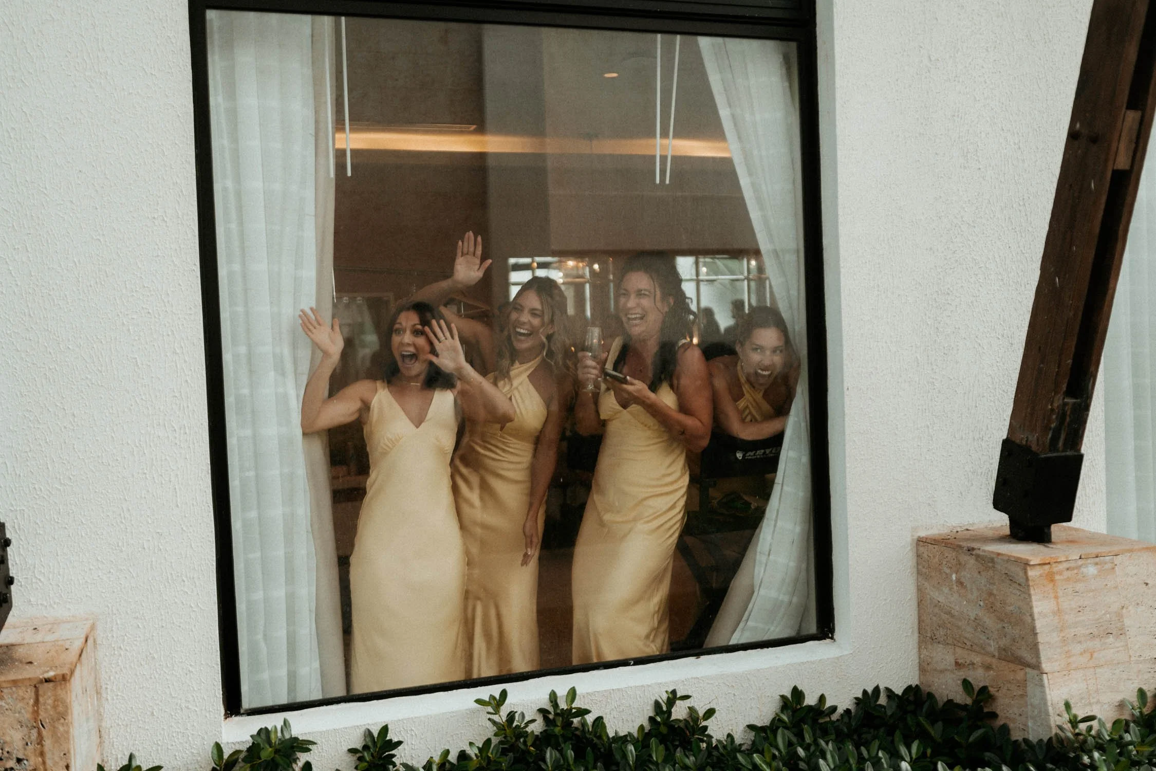 bridemaids celebrating the bride and groom through a window.