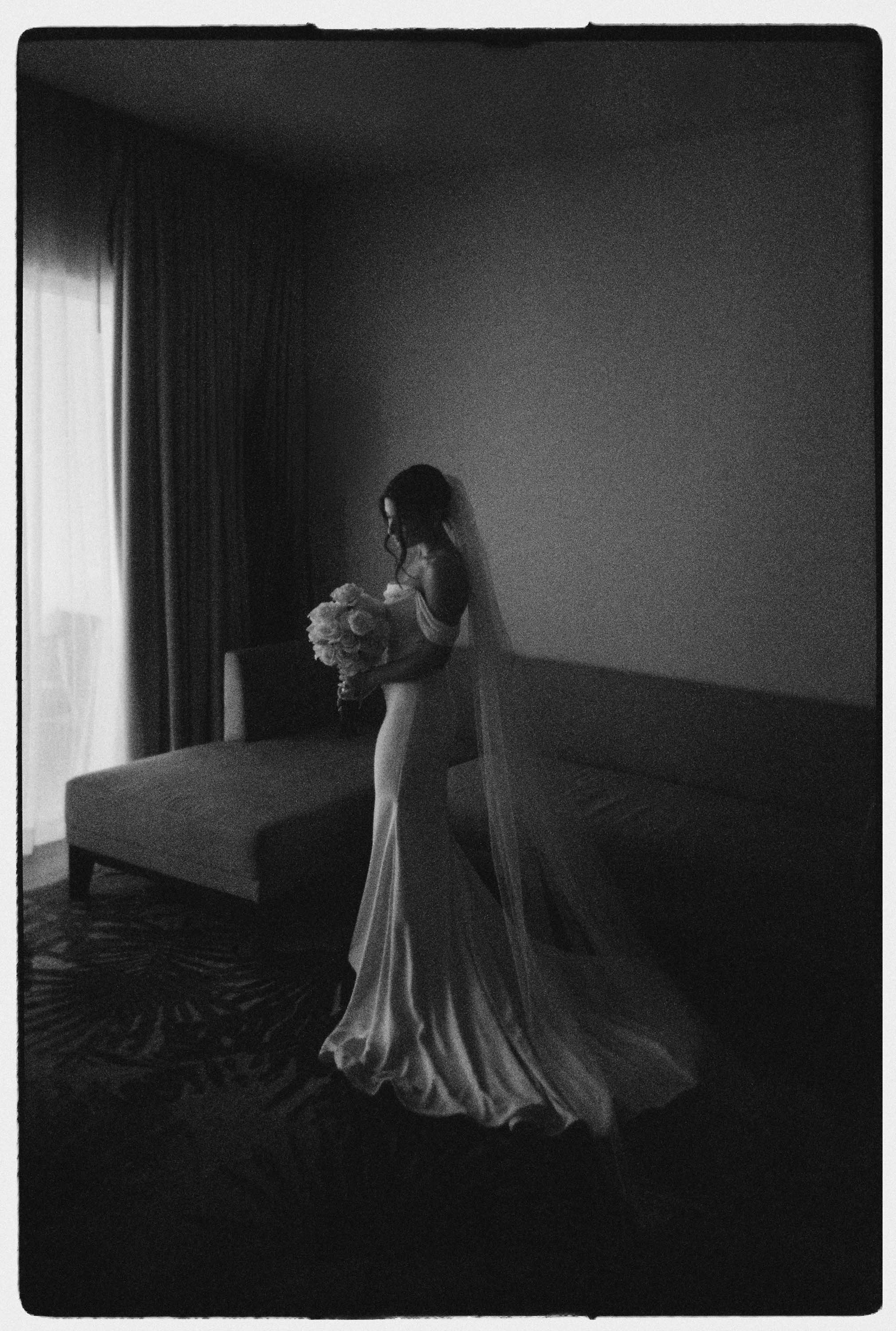 Analogue photo of bride holding the flowers in the getting ready close to a window