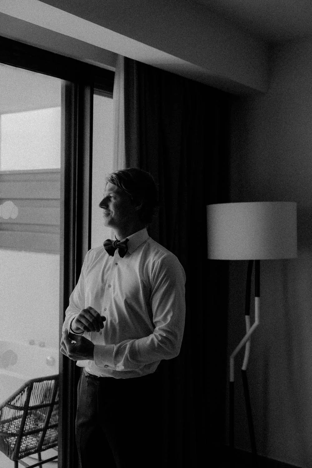 Photo in black and white of a groom getting ready while dressing up for his wedding
