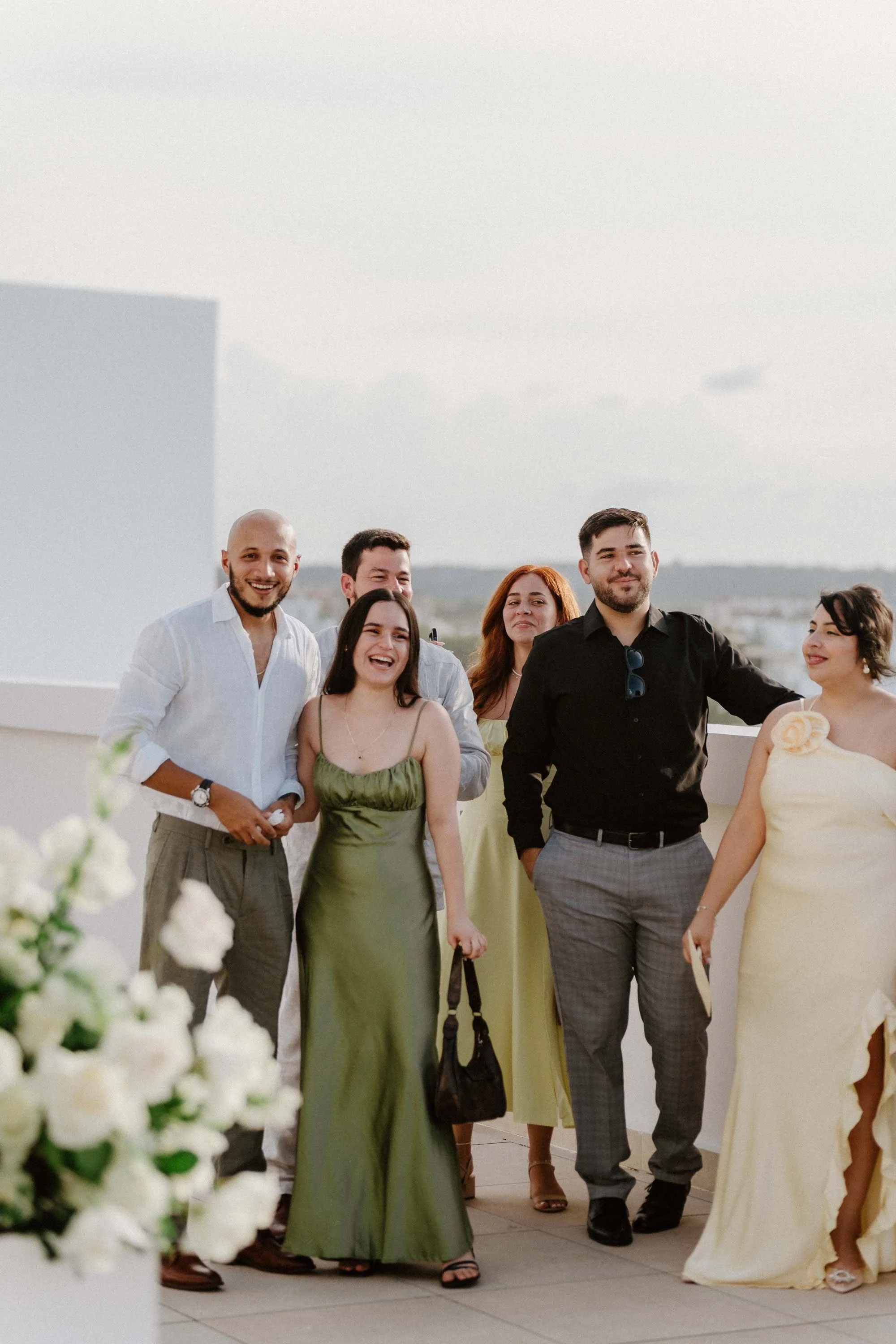 Candid photograph of joyful wedding guests in elegant, relaxed attire smiling together on a sunlit outdoor terrace during a destination wedding in Cap Cana Punta Cana.
