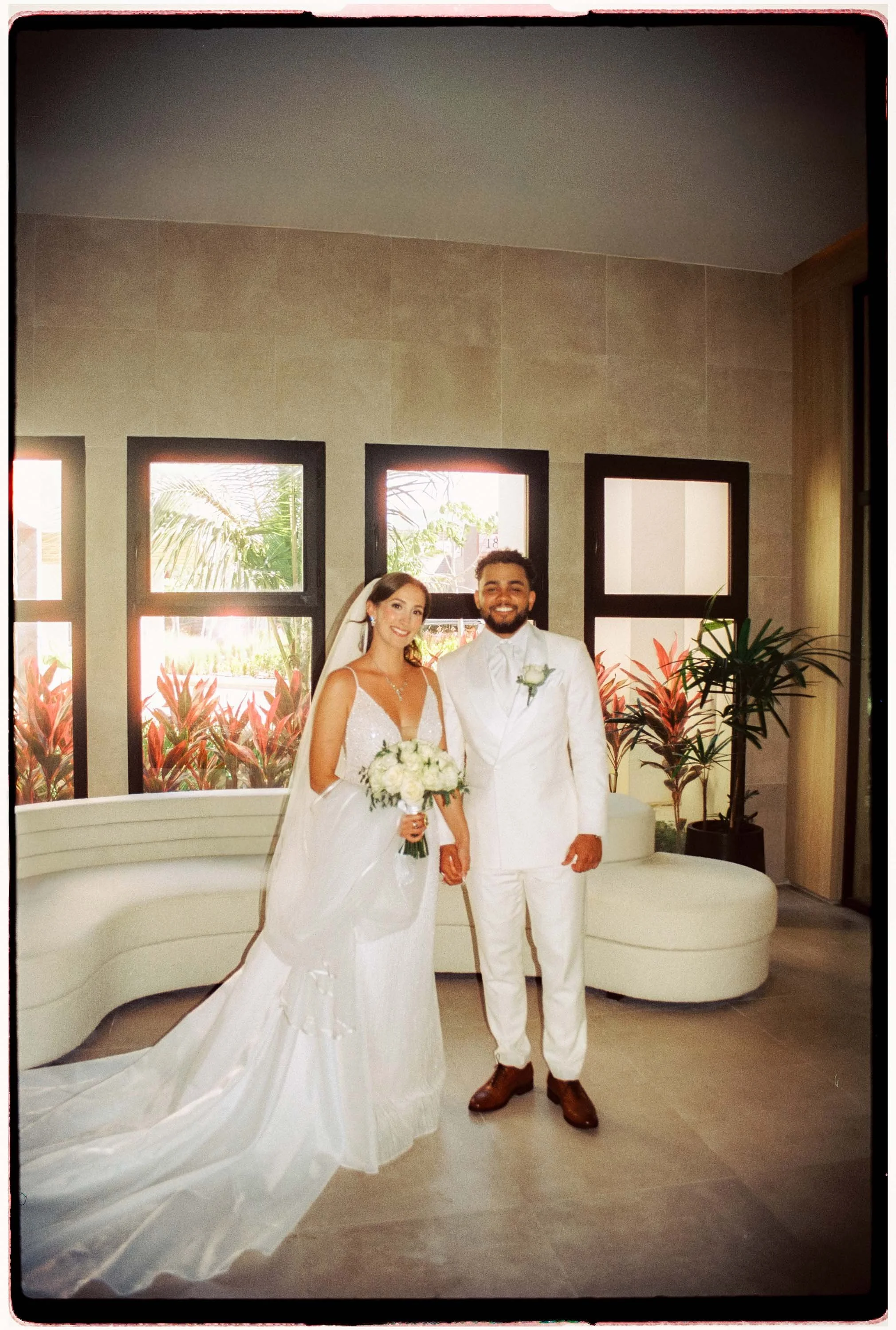 35mm film photo of couple holding hands while looking to the camera after their first look