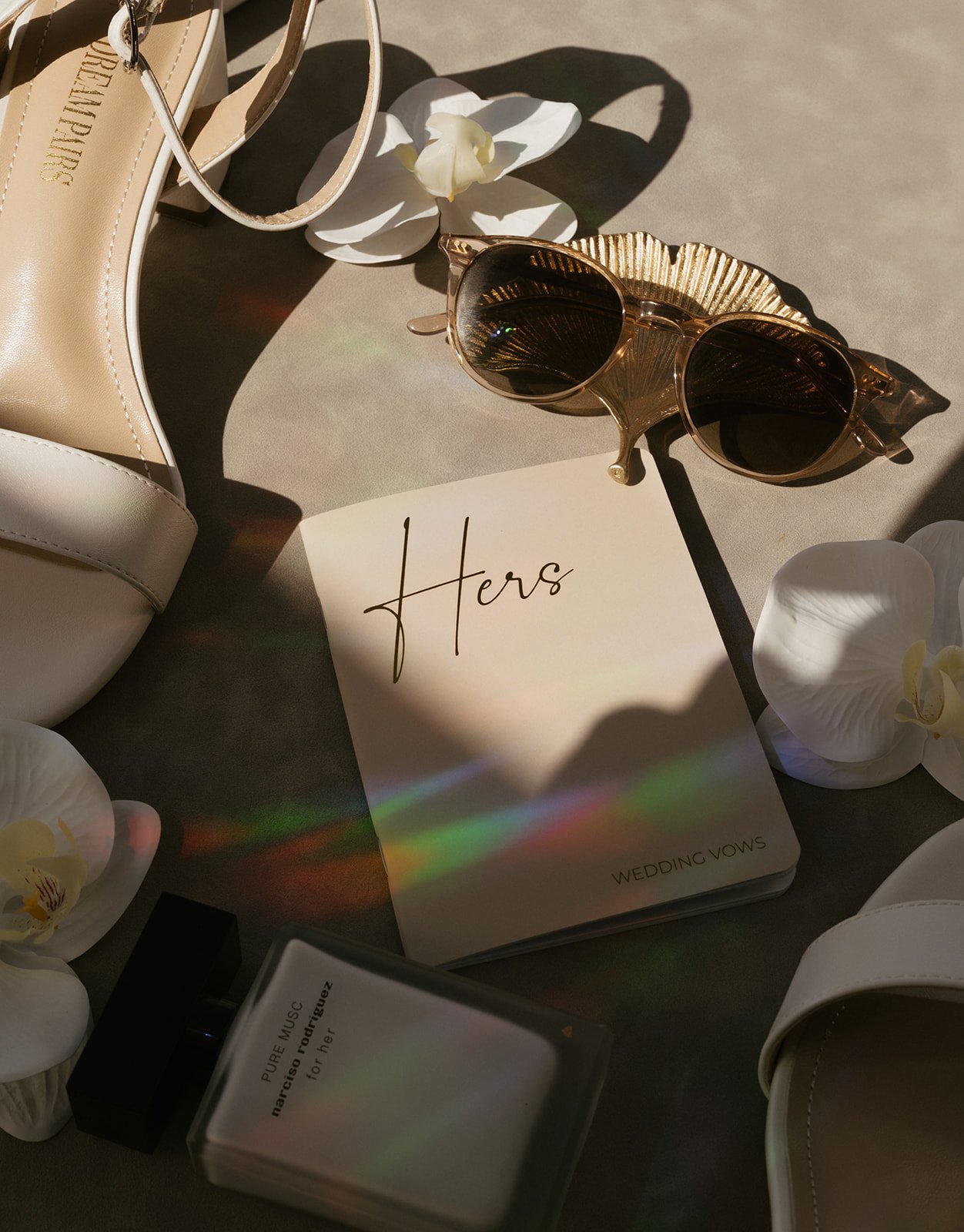 Vow and wedding details composition in a flat lay with the light of a rainbow