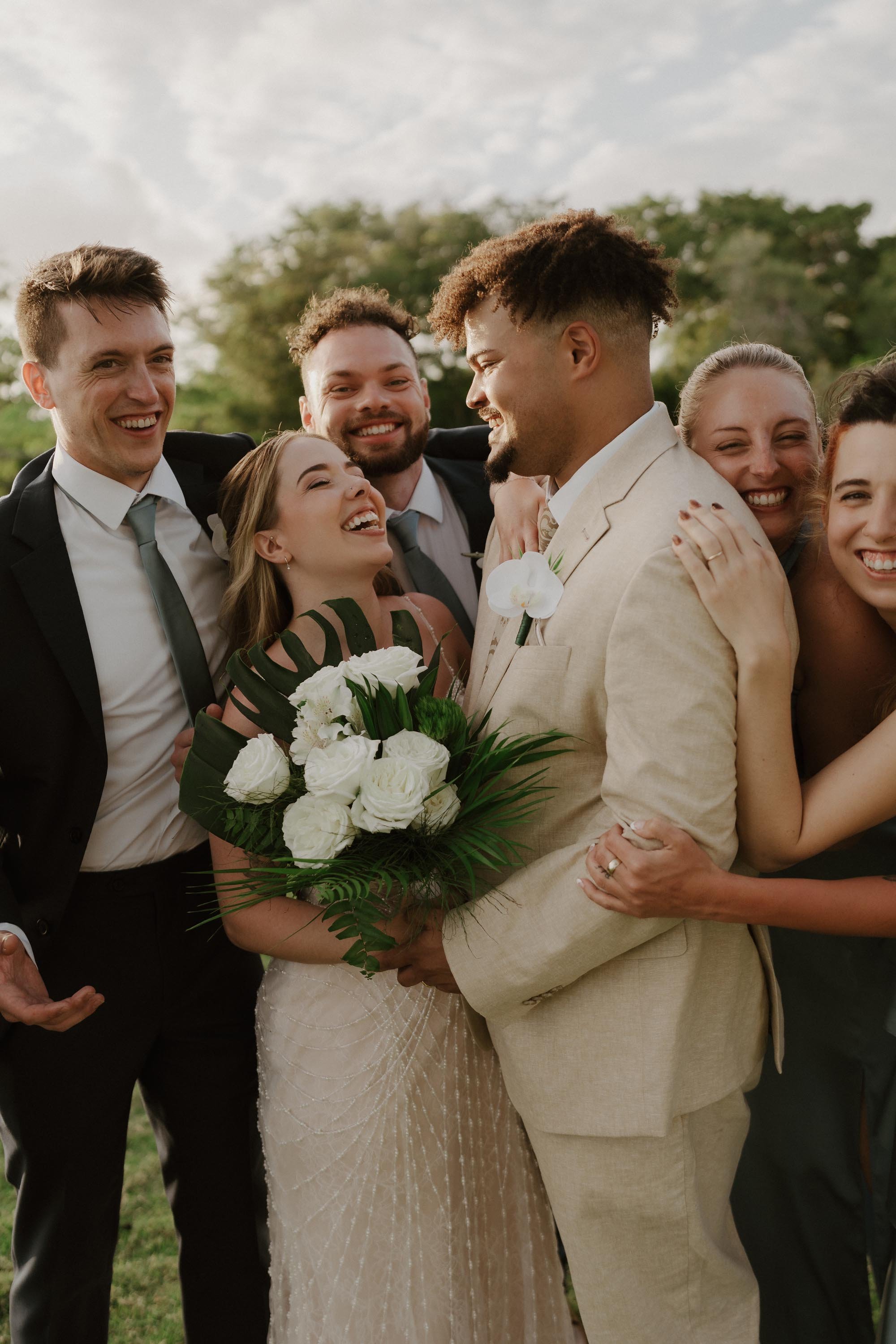 candid photo of the bride and groom while their wedding partie hug them
