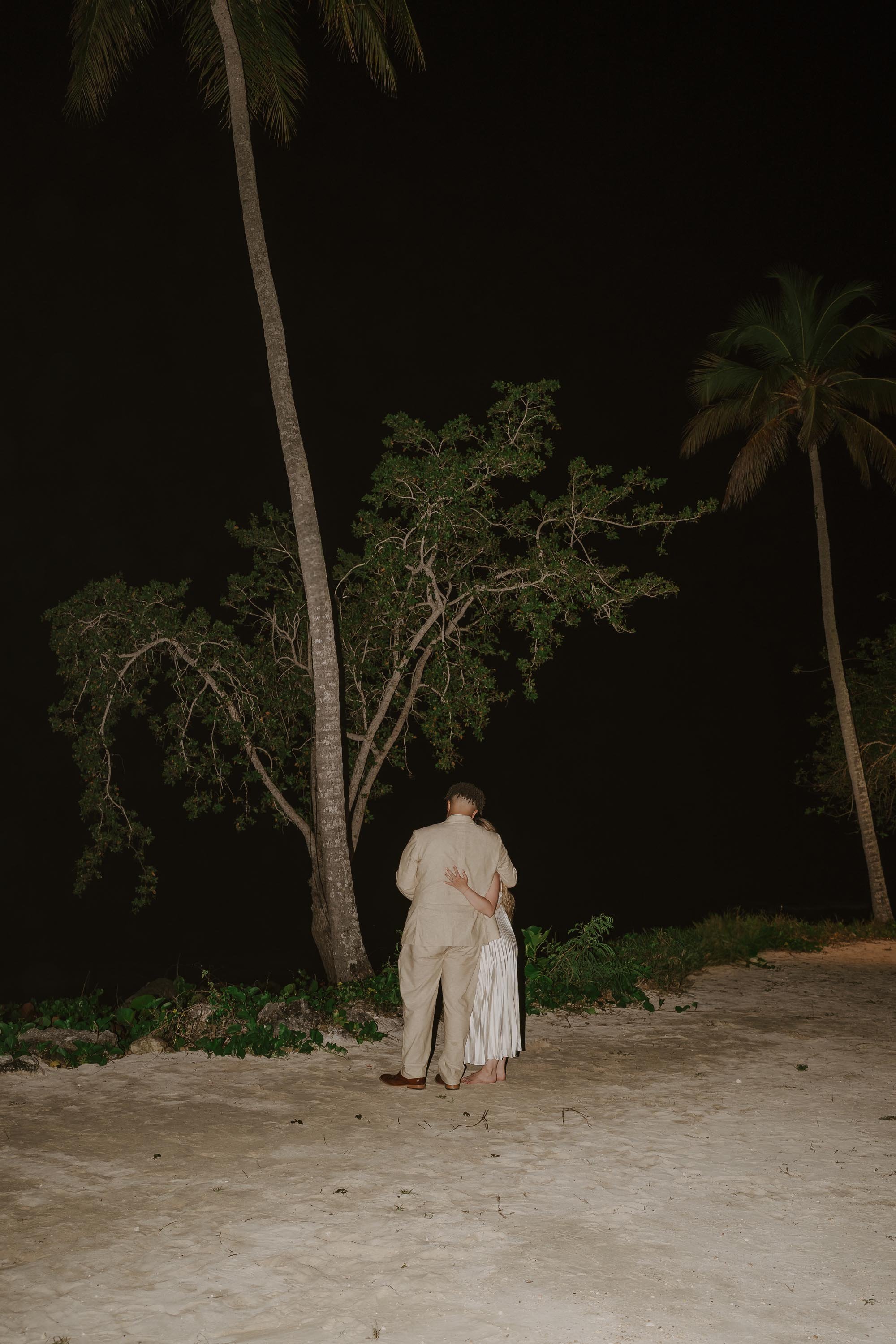 bride and groom holding each other while watching the night sky and the starts close to the beach
