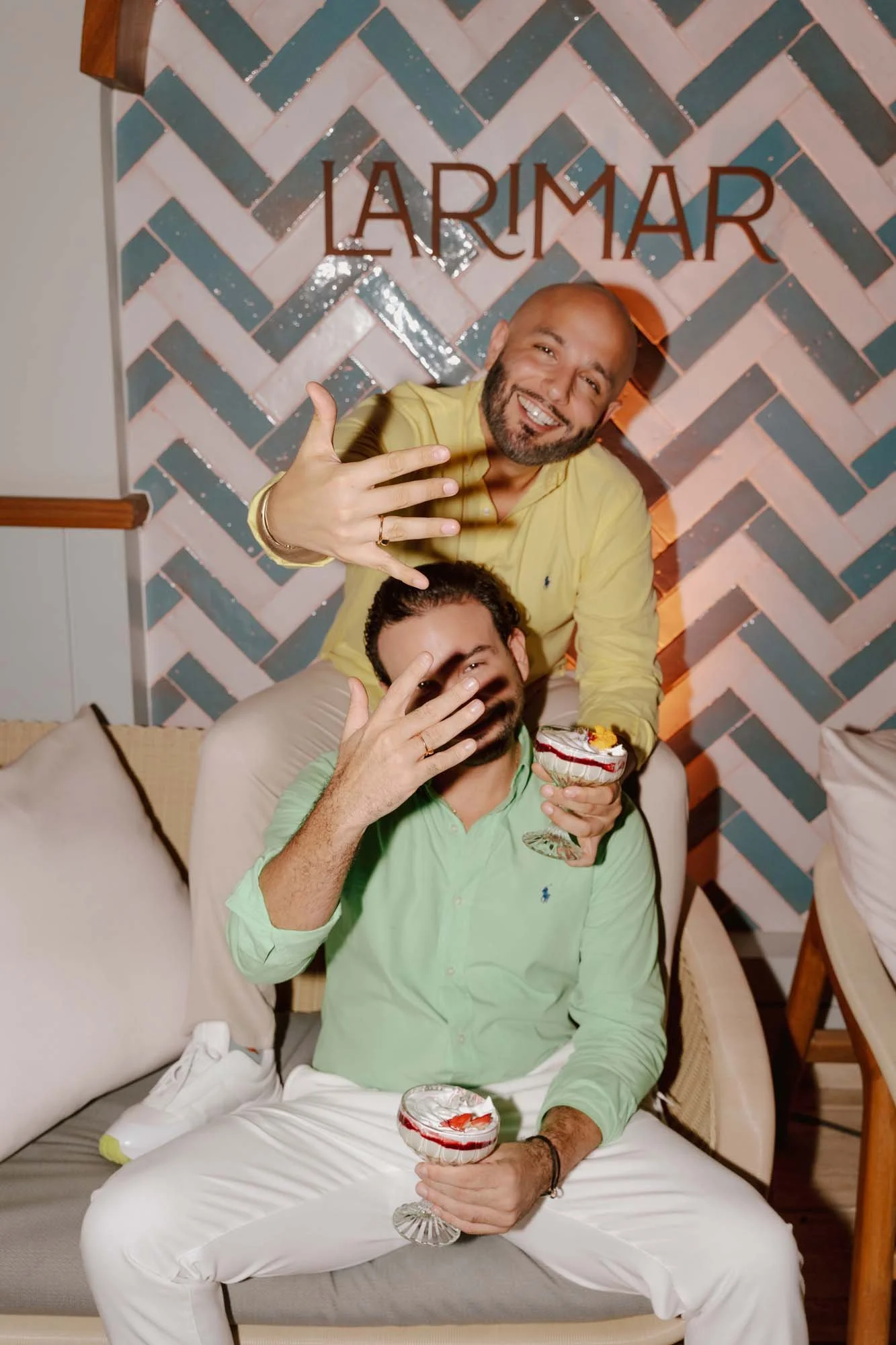 Same sex couple showing off their engagement rings while holding a cup of dessert
