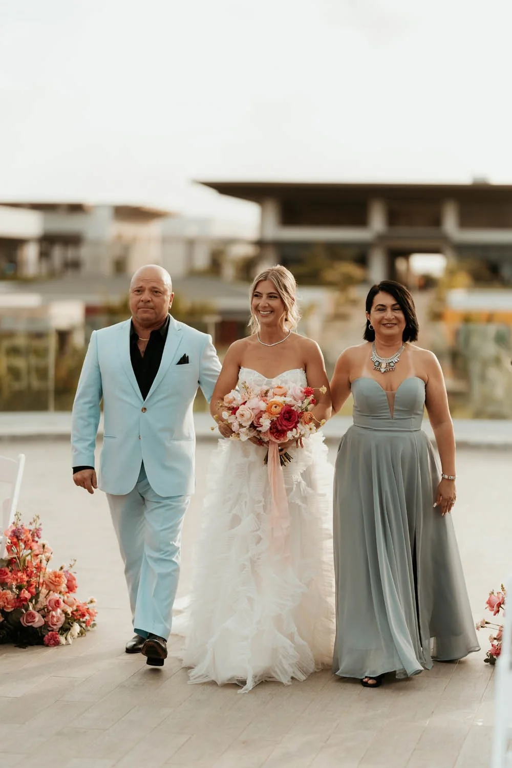 Bride walking with mom and dad towards the ceremony