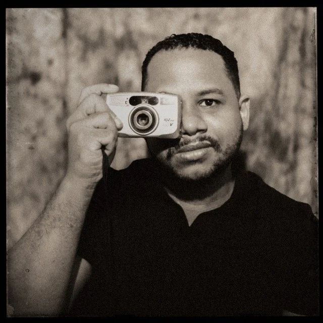 A wedding photographer in a vintange style photo holding a camera and taking a photo