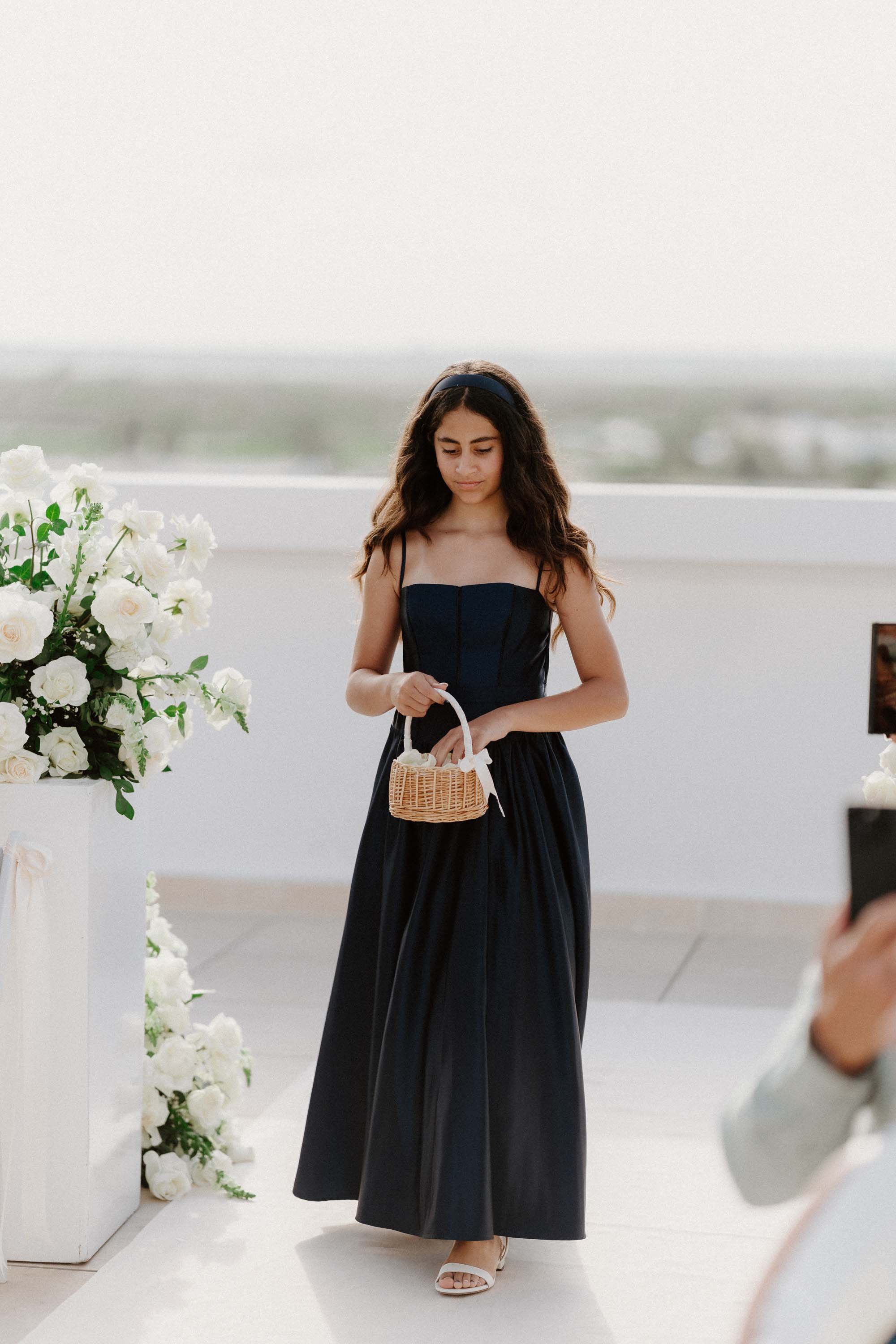 "An editorial, sweet photograph of the couple's daughter acting as the flower girl, holding a small woven basket as she walks down the aisle during an intimate destination wedding in Cap Cana Punta Cana."