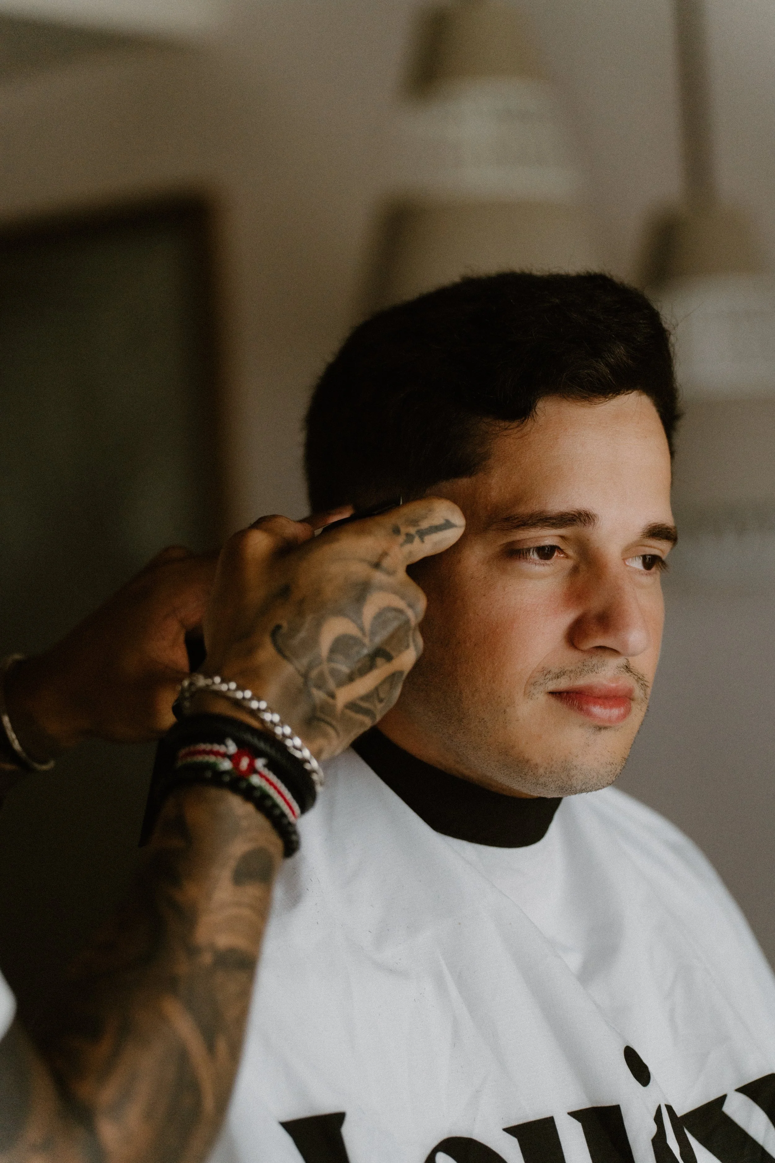 A candid, storytelling moment of the groom sharing a laugh while getting a fresh haircut from his best friend during the wedding morning preparations in Cap Cana Punta Cana