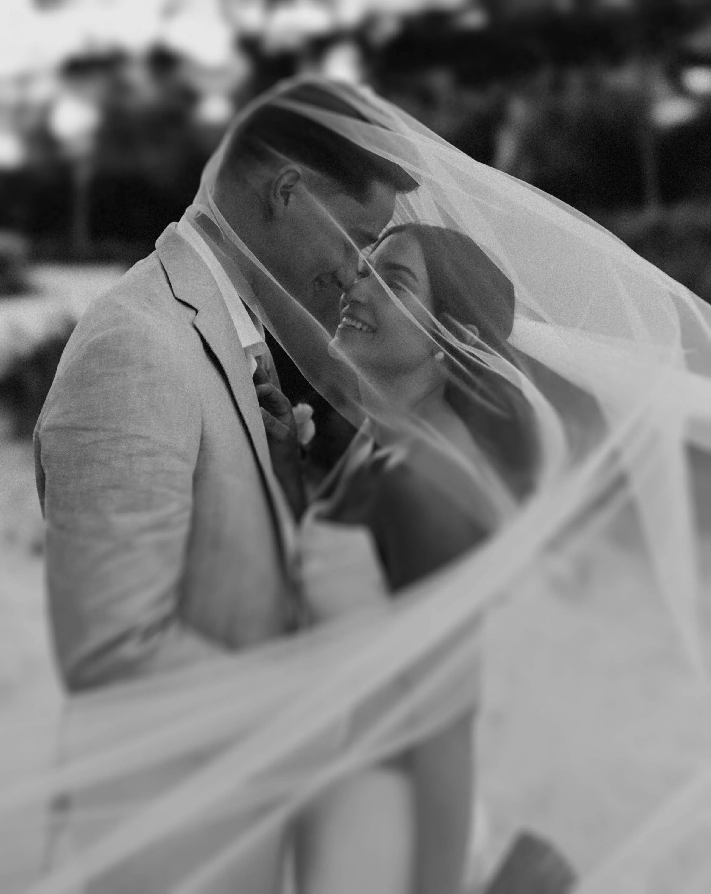 Bride and groom under veil kissing