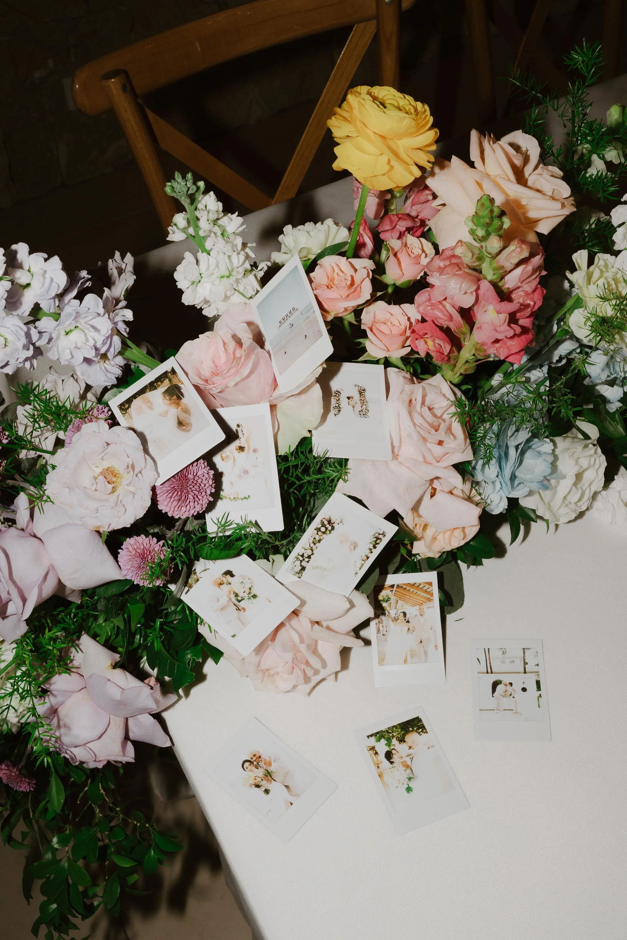 Polaroid photos of the bride and groom scattered among pastel floral centerpieces on a reception table at Kukua Beach Club in Punta Cana.