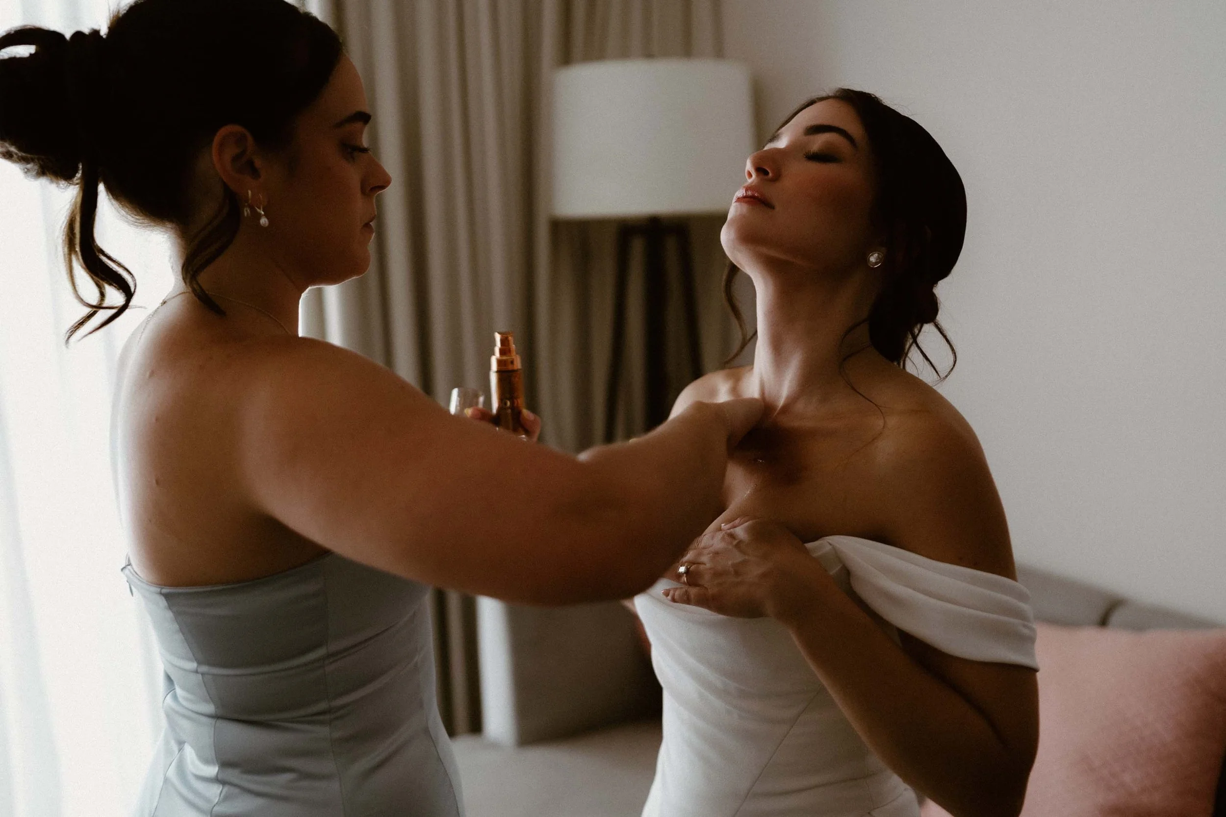 Bridemaid helping the bride getting her makeup done